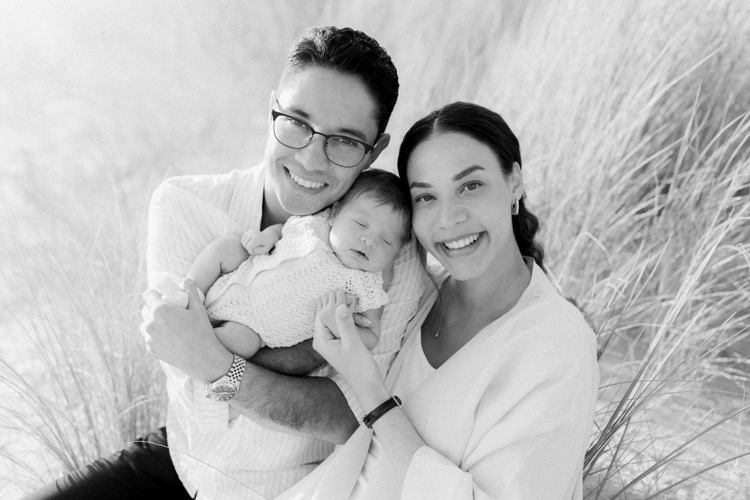 Family portrait session in tall grass with soft natural lighting.