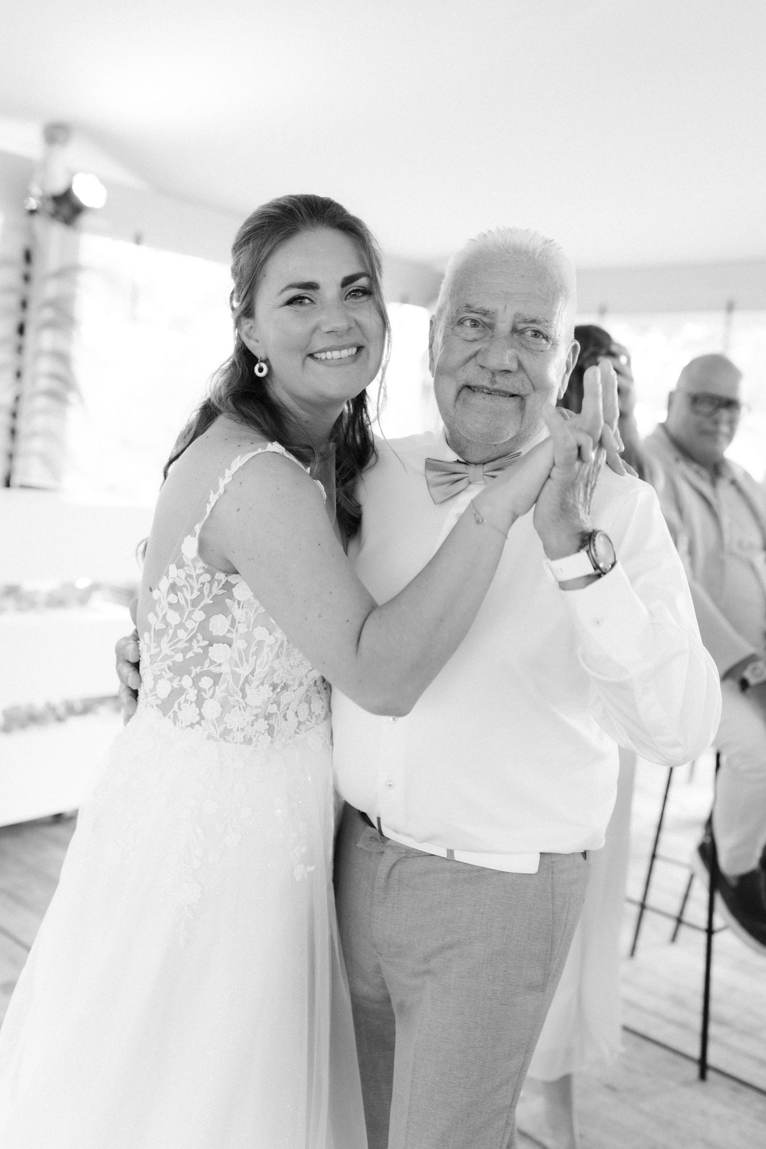 Bride and father share a joyful dance at wedding reception, black and white photo.
