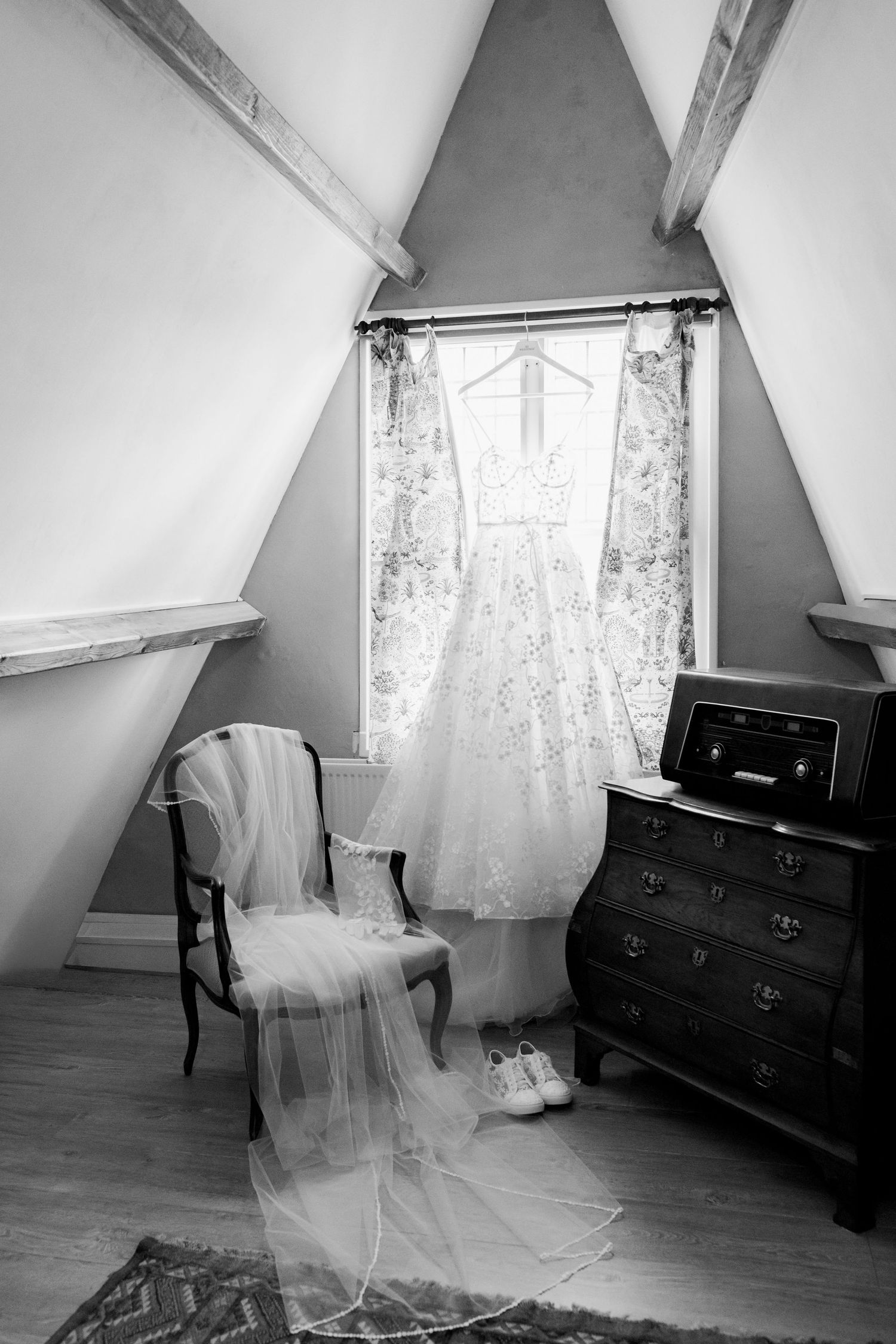 A sequence of black and white photos showing a ghostly white dress floating in an empty attic room with slanted walls.