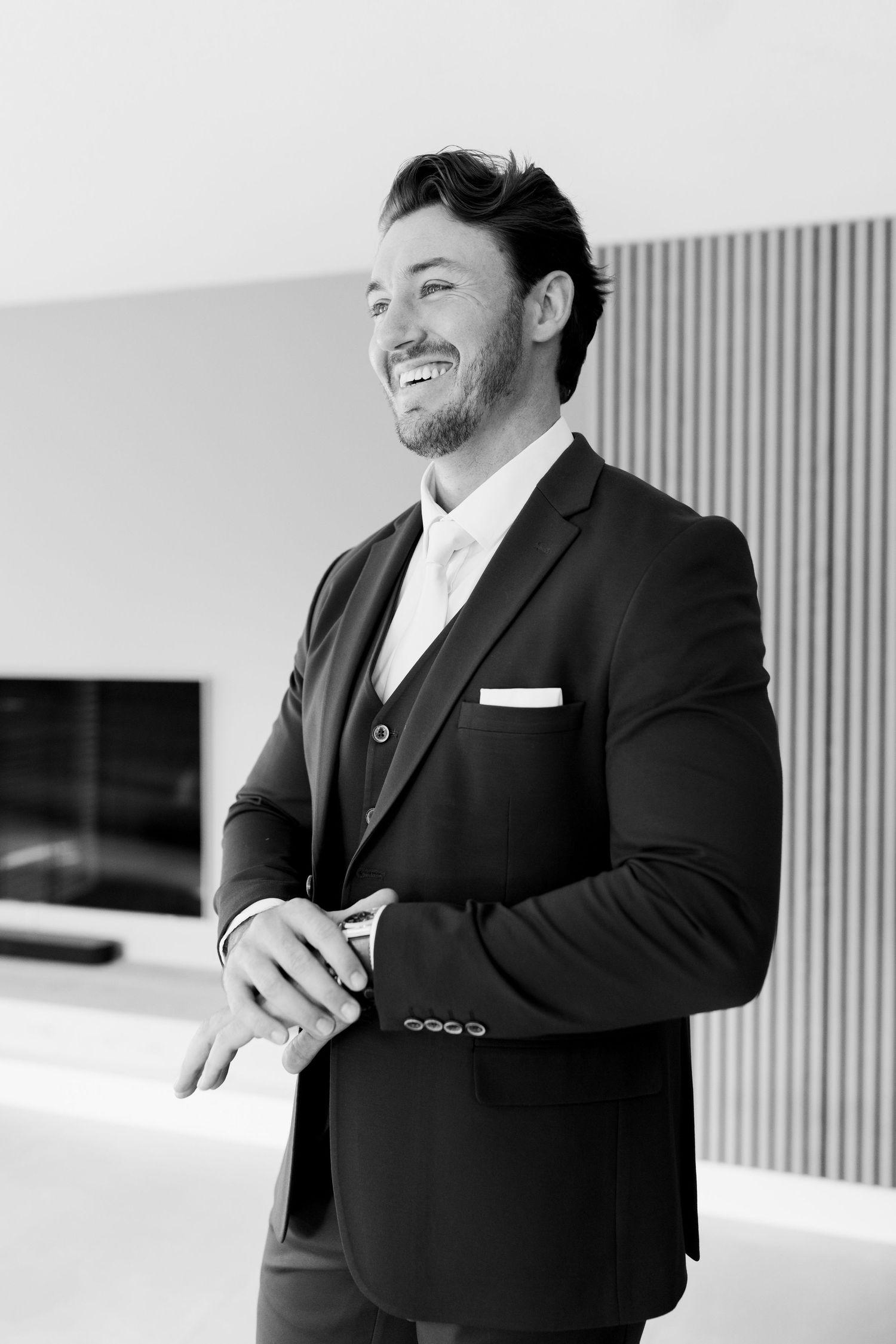 A black and white photo series showing candid moments of a person in a suit laughing and smiling.