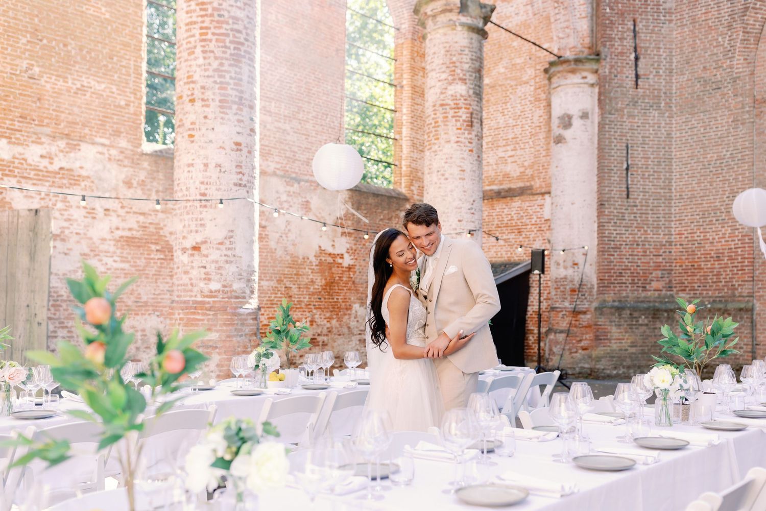 Romantic wedding table setup in a rustic brick venue with soft natural lighting and floral centerpieces.