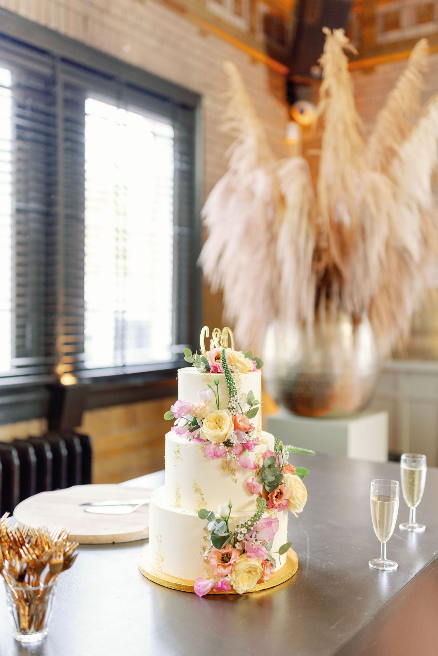 A series of elegant wedding cakes with floral decorations displayed on tables with champagne glasses and ethereal decor.