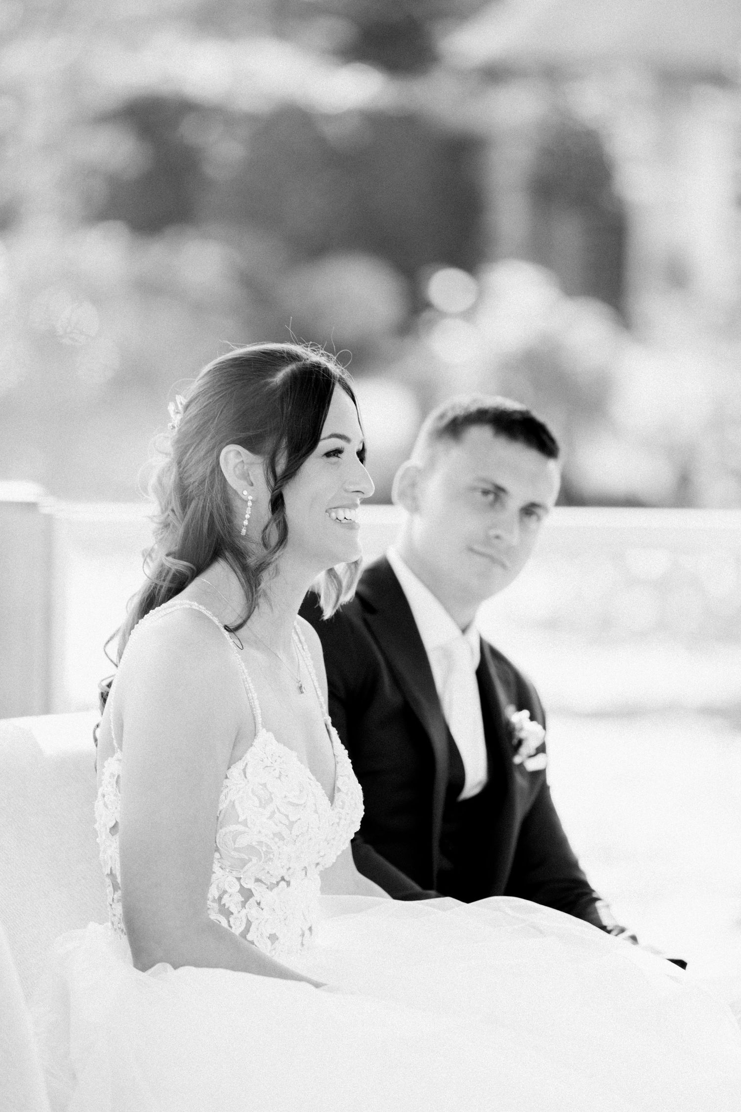 Black and white photo of a couple sitting together during their wedding ceremony.