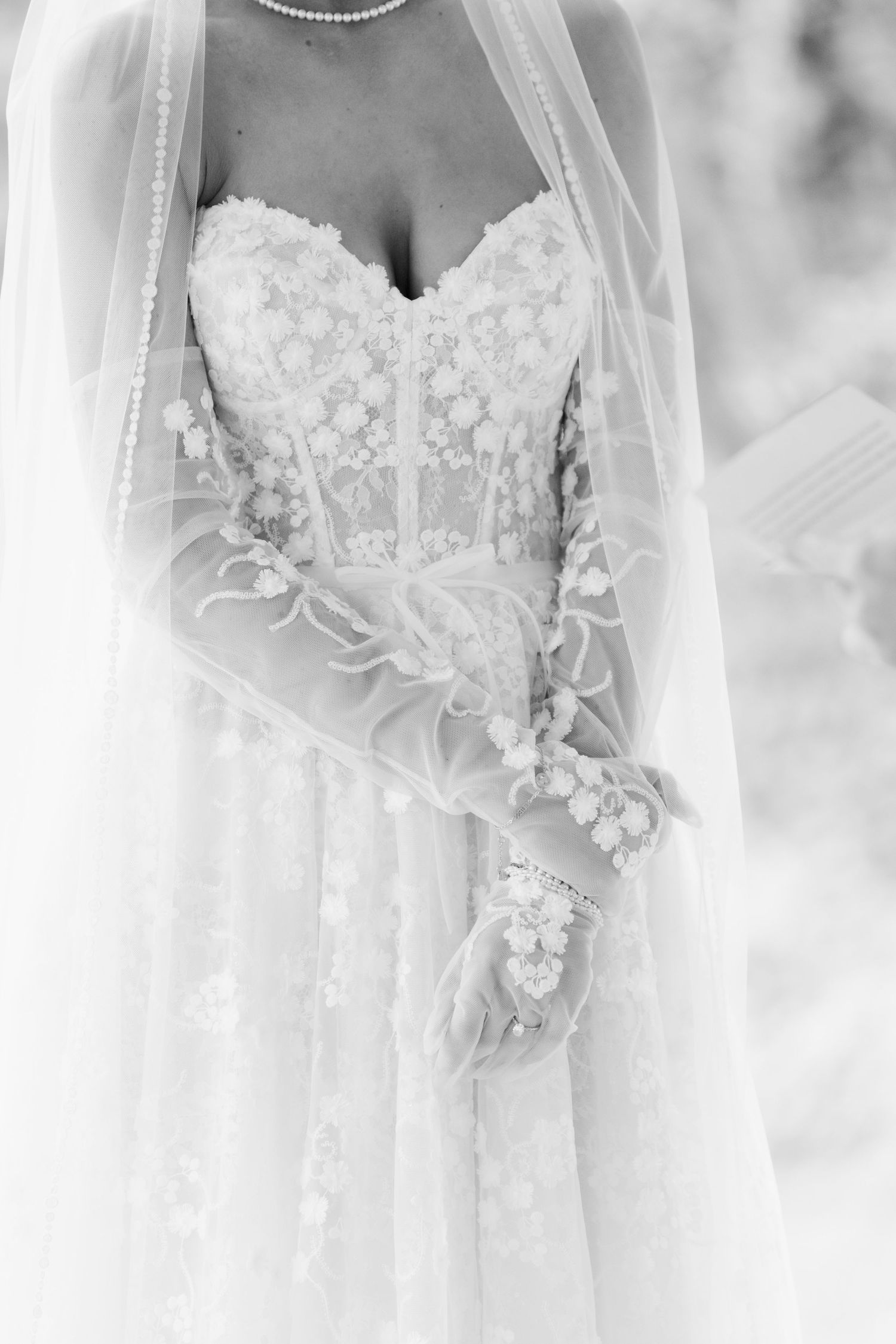 Close-up details of delicate white lace wedding dresses with floral embellishments and beading.