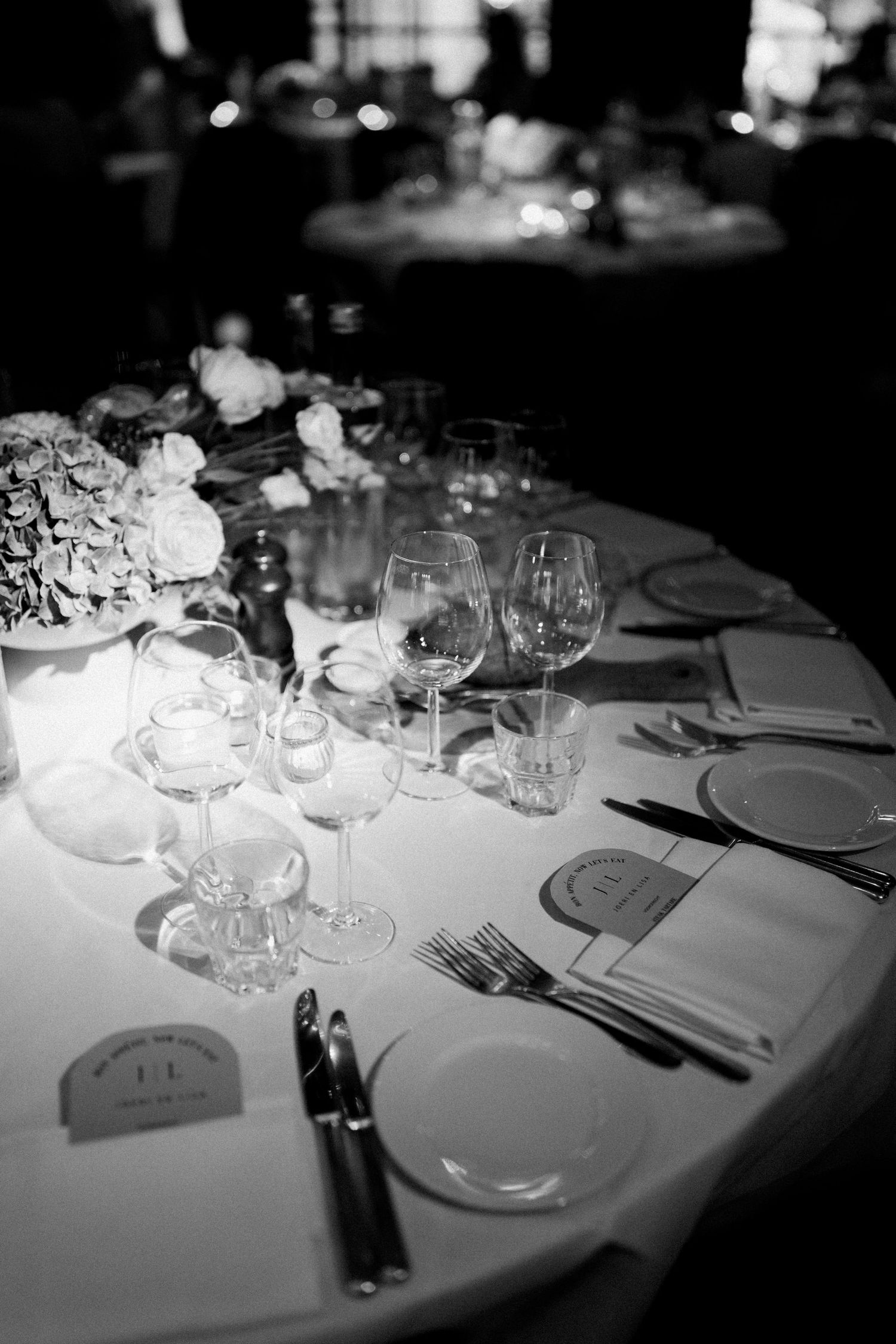 Elegant black and white table settings with wine glasses and white plates arranged for a formal dining event.