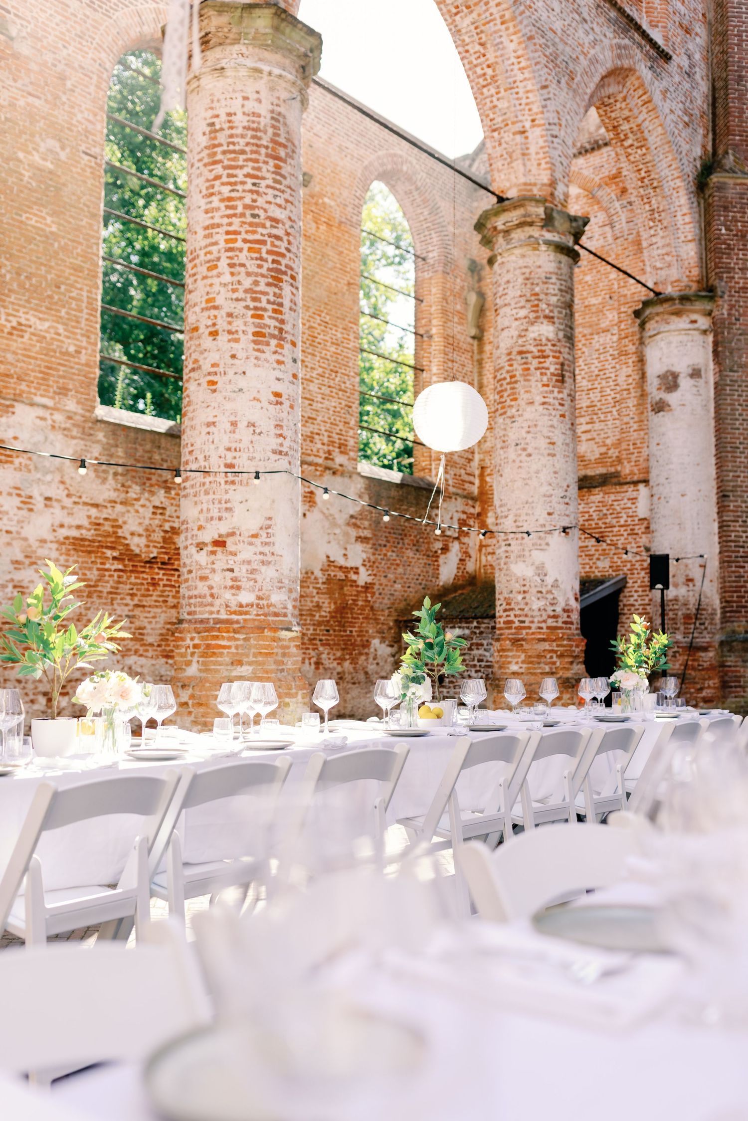White folding chairs arranged in rows beneath historic brick archways for an elegant outdoor wedding ceremony setup.