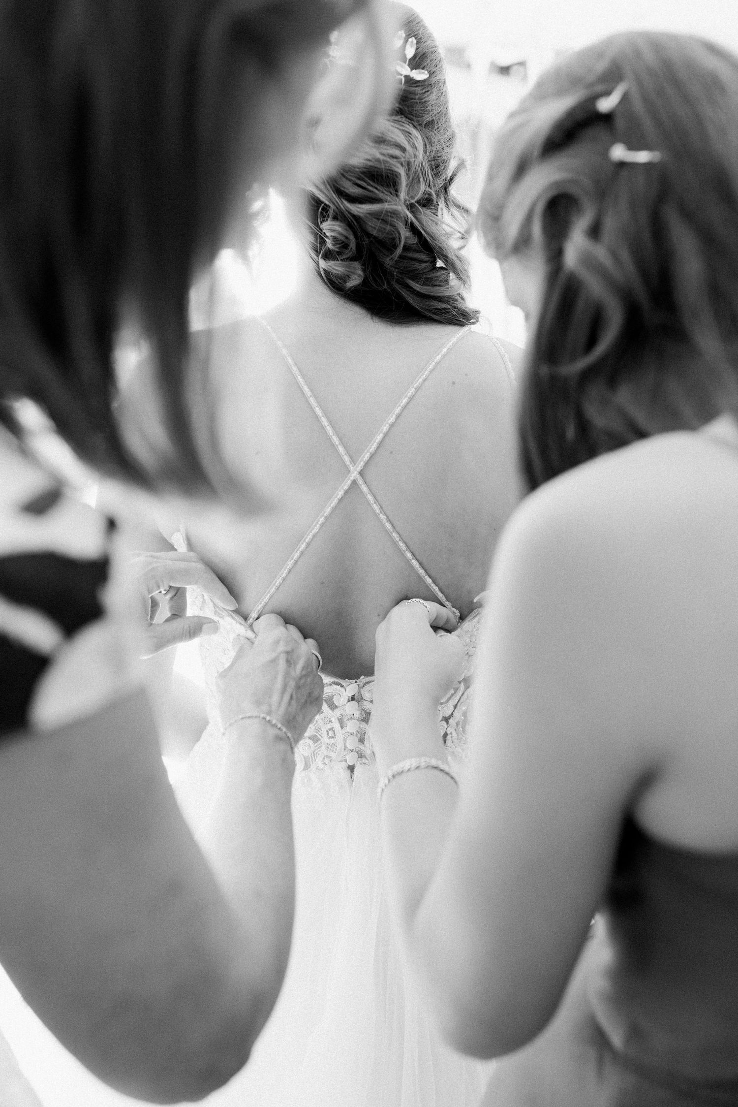 Close-up black and white photo showing intricate lace detail and criss-cross straps on back of wedding dress.