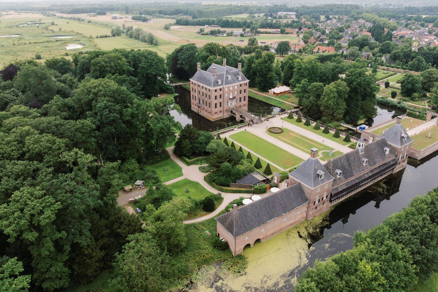 Aerial view of historic Dutch castle Muiderslot surrounded by moat and lush green gardens.