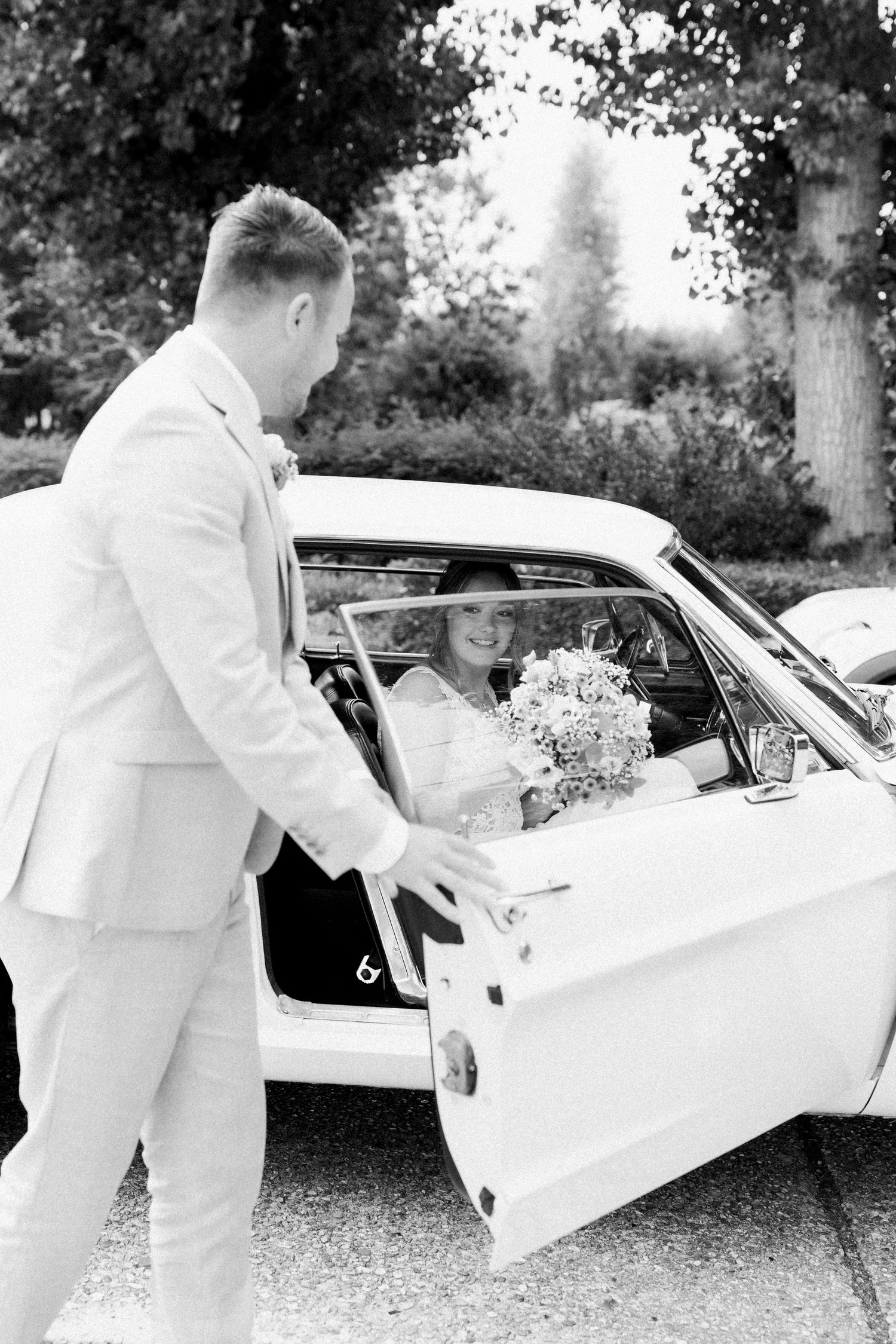 Black and white sequence of photos showing a bride in a flowing dress getting into a vintage car.