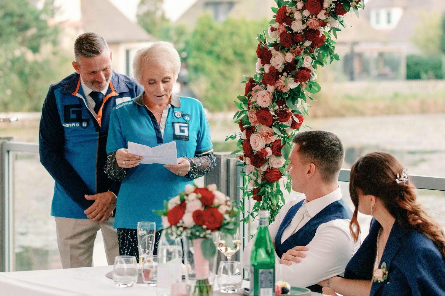 Guests gathered at outdoor reception with red floral decorations.