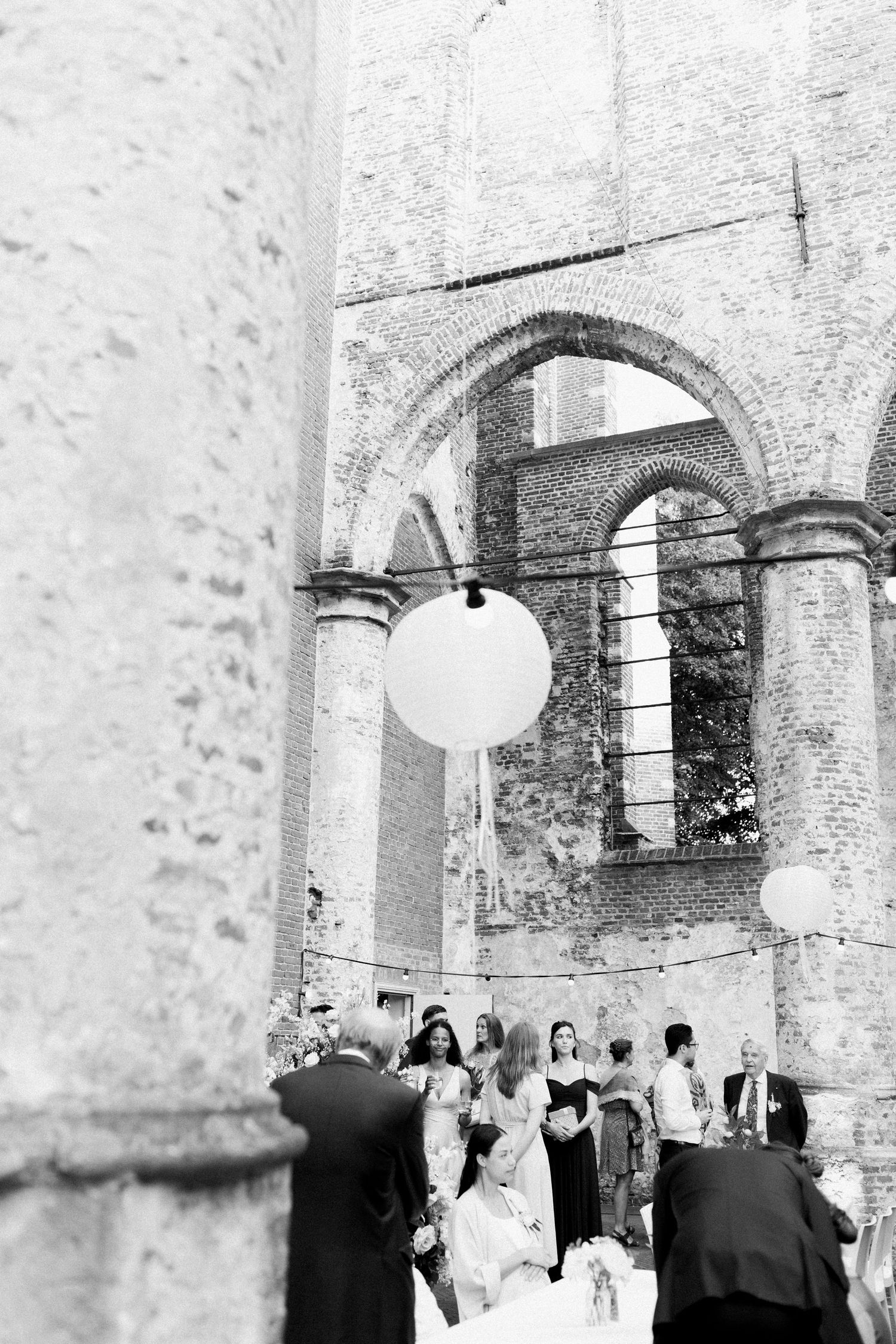 Guests gather under stone archways at an elegant wedding reception venue with historic architectural details.