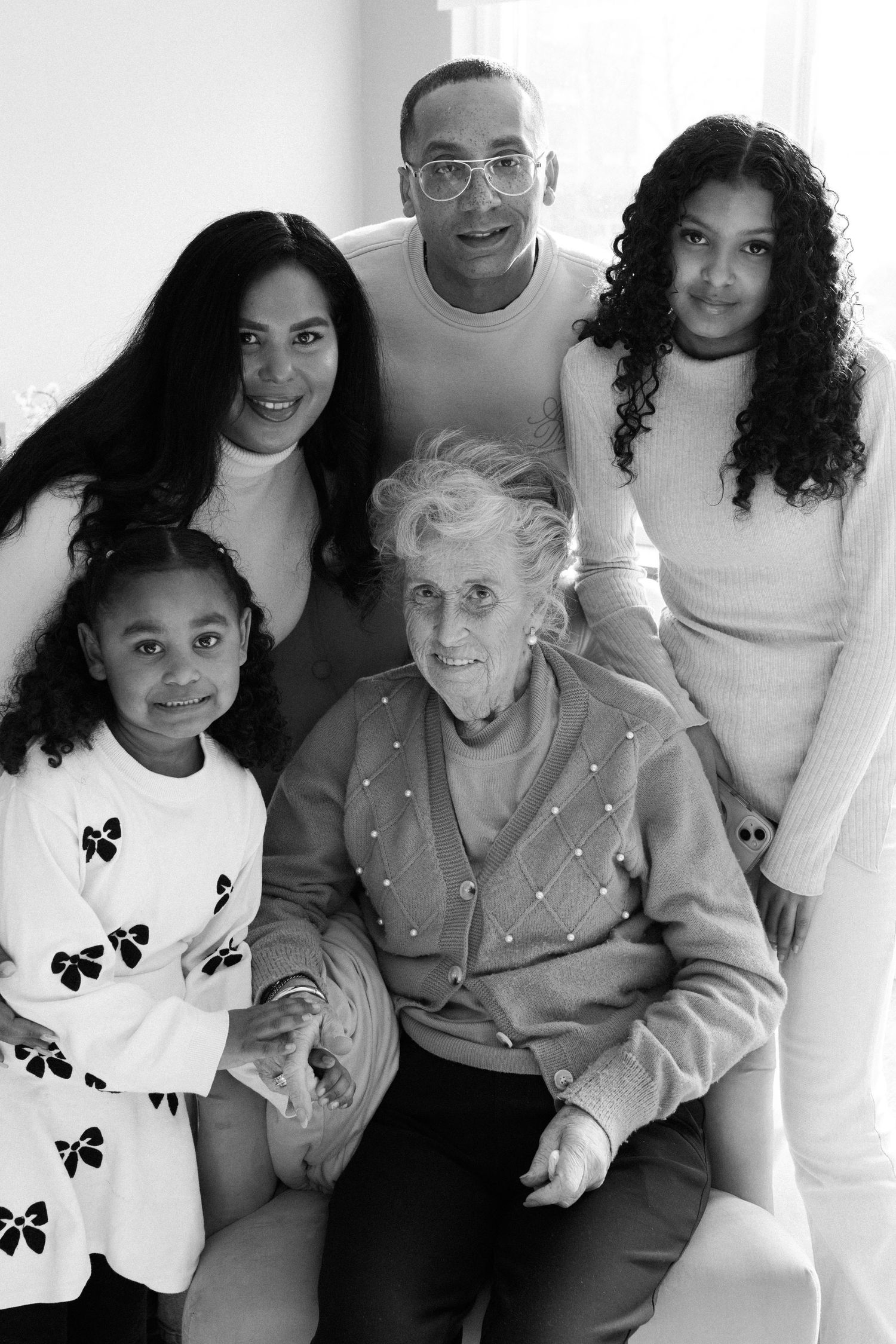 Black and white photo of a family group wearing white and gray clothing posing together.