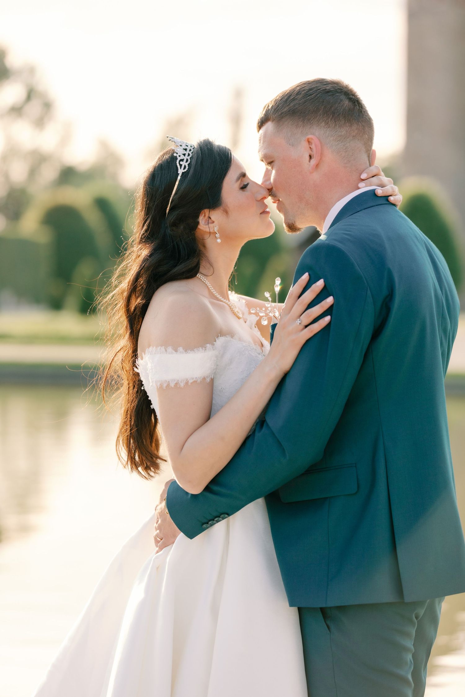 A romantic sunset wedding portrait with couple embracing by a lake.