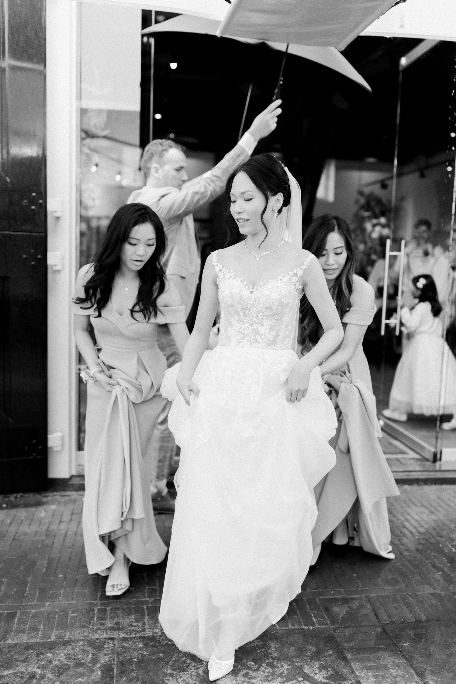 A bride in a white wedding dress dances with bridesmaids in light colored dresses during a celebration.