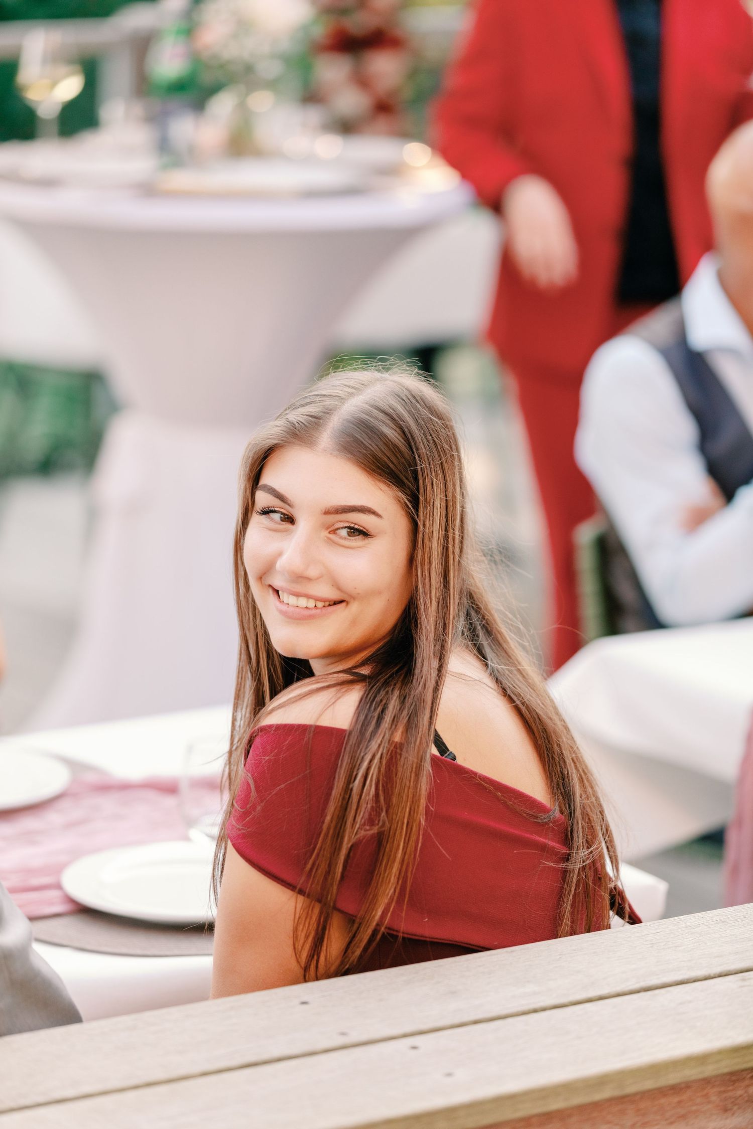 Wedding guest in red enjoying an outdoor reception.