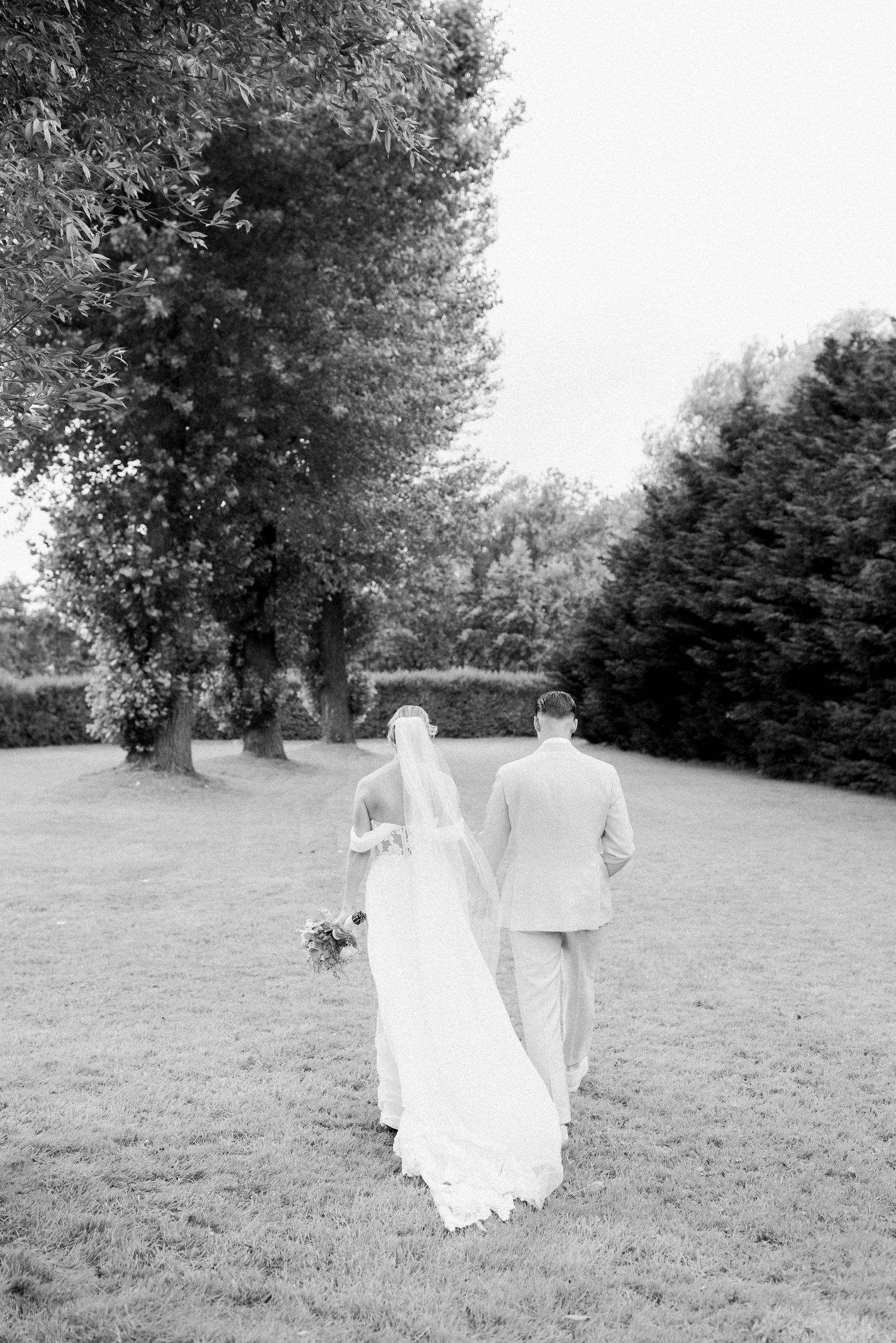 Black and white photograph of a couple walking through a serene garden landscape.