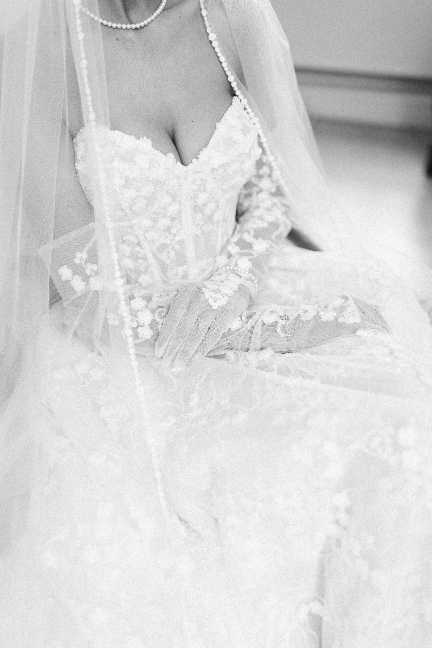 Close-up detail of delicate lace wedding dress and veil in black and white.