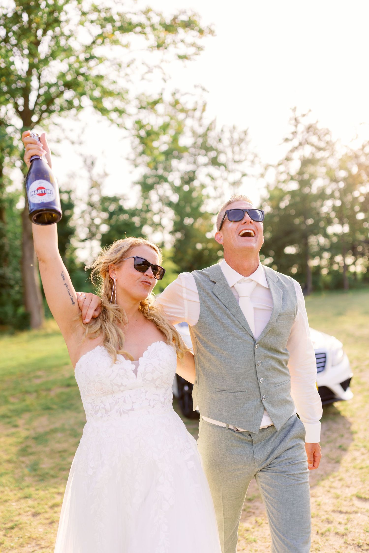 Celebratory moment of newlyweds cheering with drinks outdoors.