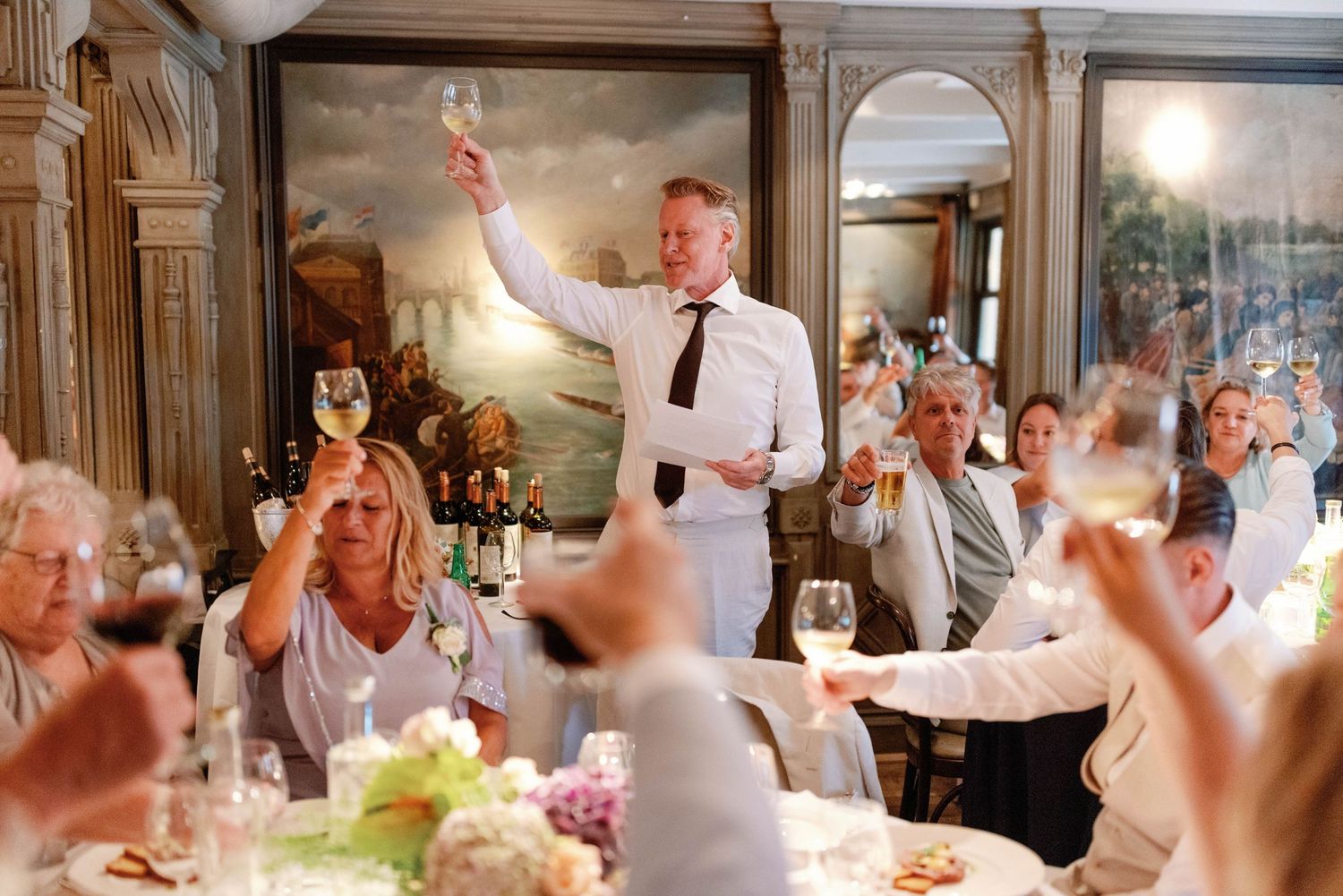 Wedding guests enjoying a celebration in an elegant reception hall with warm lighting and festive atmosphere.