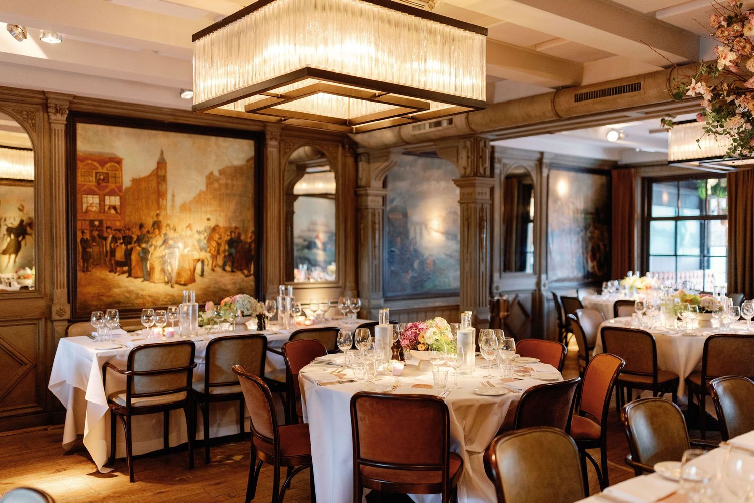 Elegant restaurant dining room with round tables, white tablecloths, and warm lighting showcasing traditional decor and ambiance.