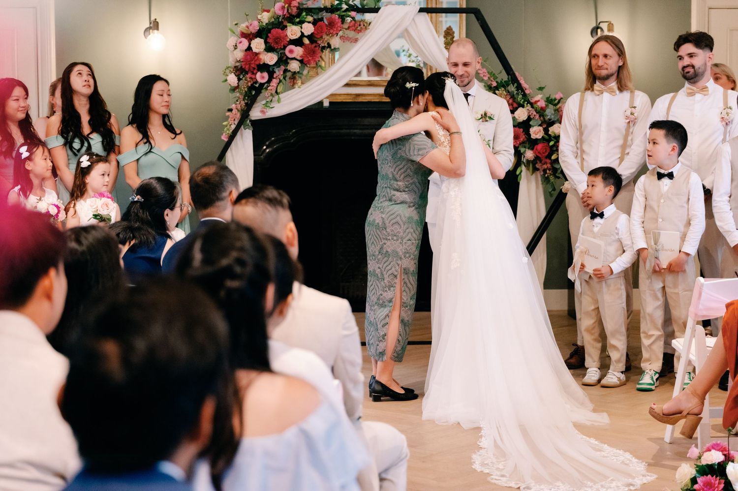 A group of people in white attire dance and celebrate together at a festive indoor party.