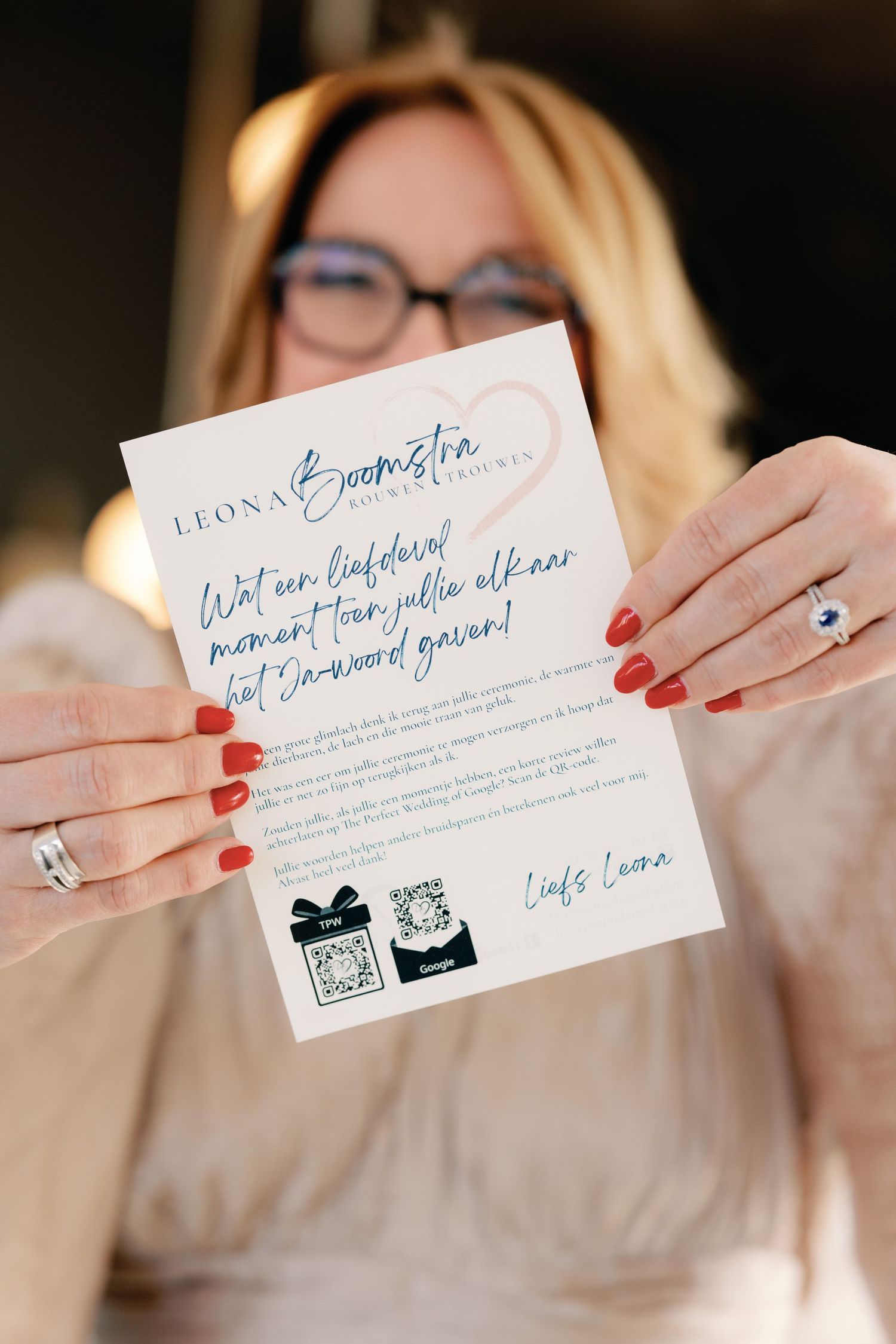 A series of hands holding elegant wedding invitation cards with blue calligraphy and red nail polish.