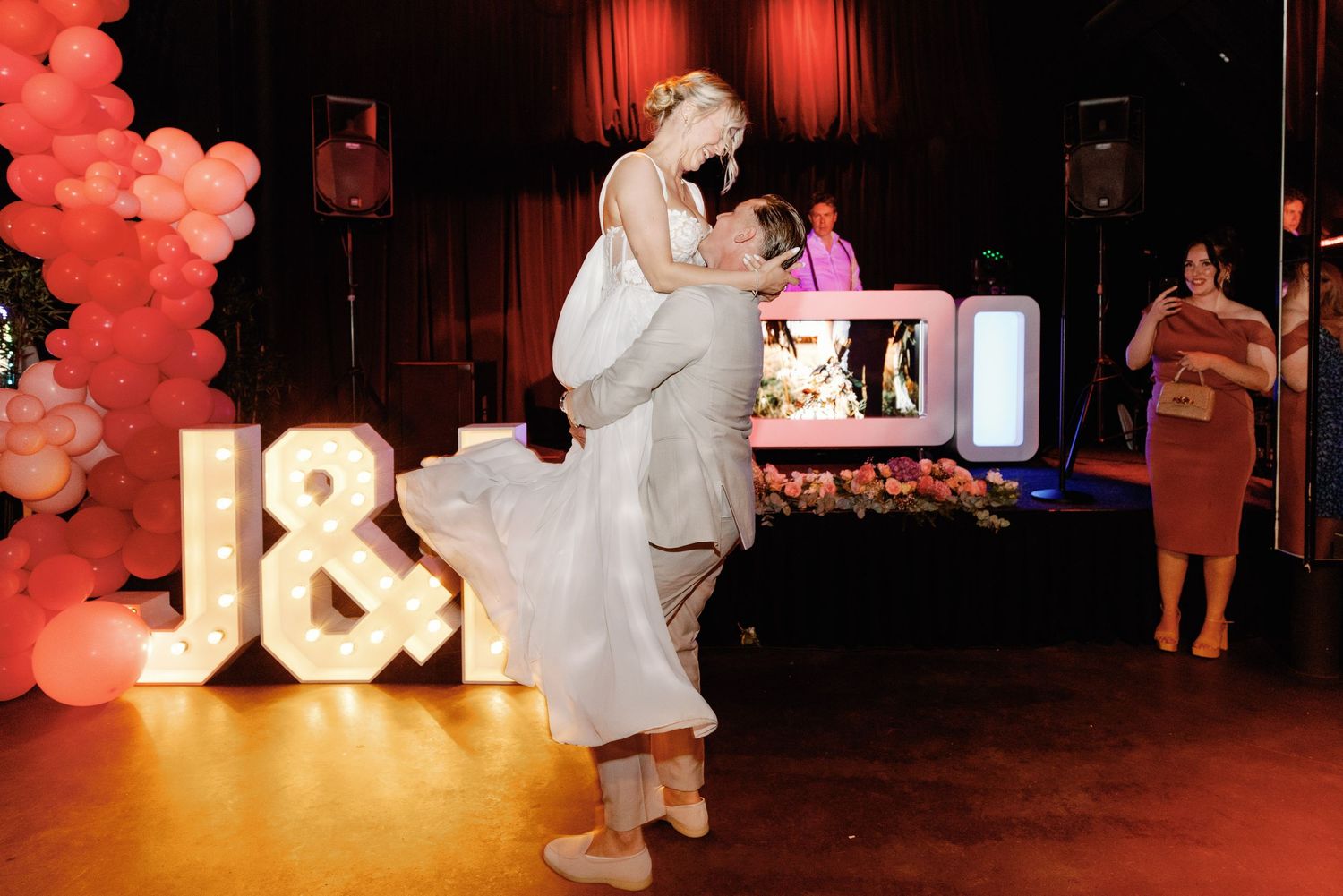 Red balloons create a festive atmosphere at an indoor event with dramatic lighting and decorative elements.