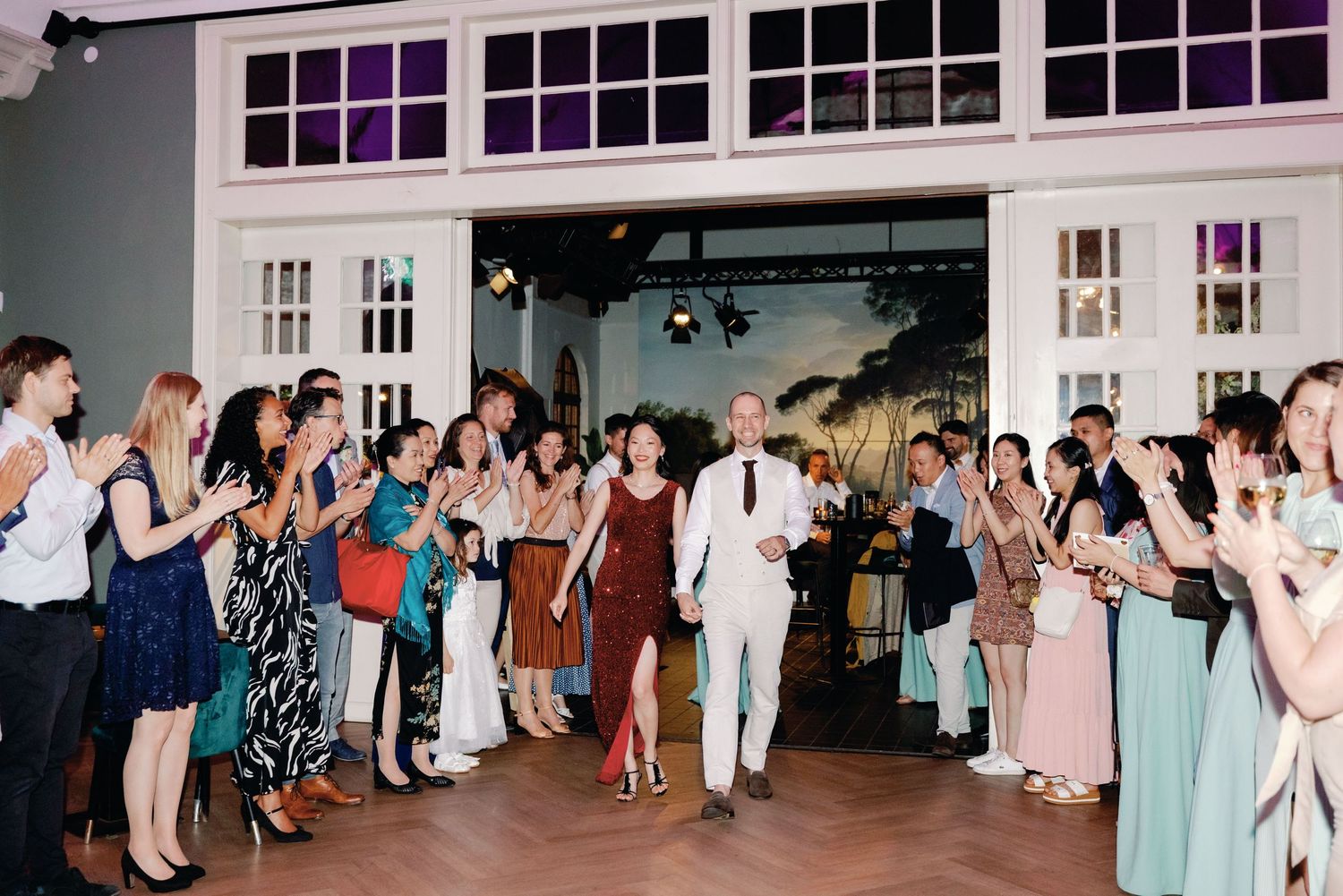 Wedding guests form a cheering line on the dance floor as a couple walks through during a reception celebration.