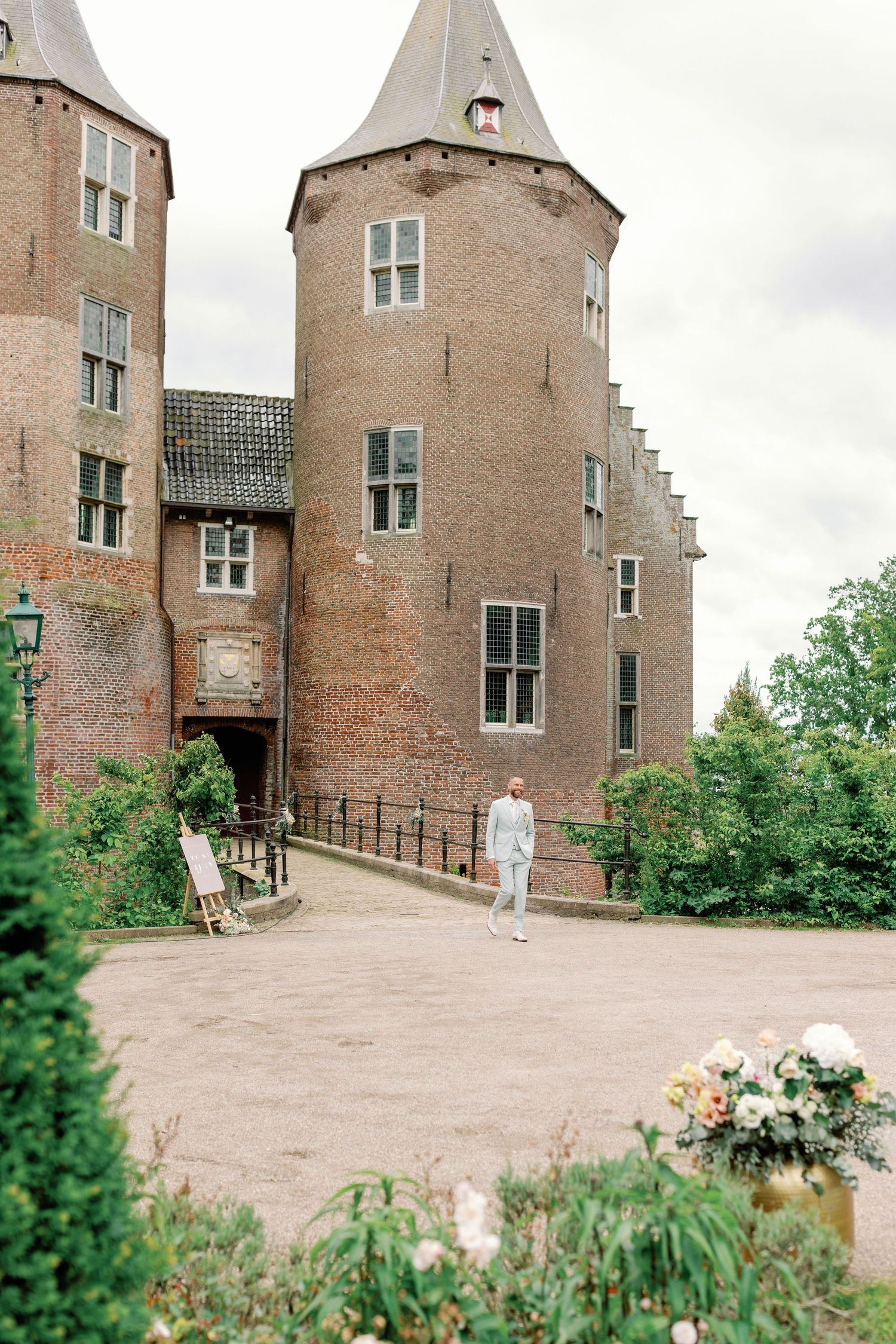 Historic brick castle exterior with stepped gables and windows surrounded by lush greenery and garden landscaping.