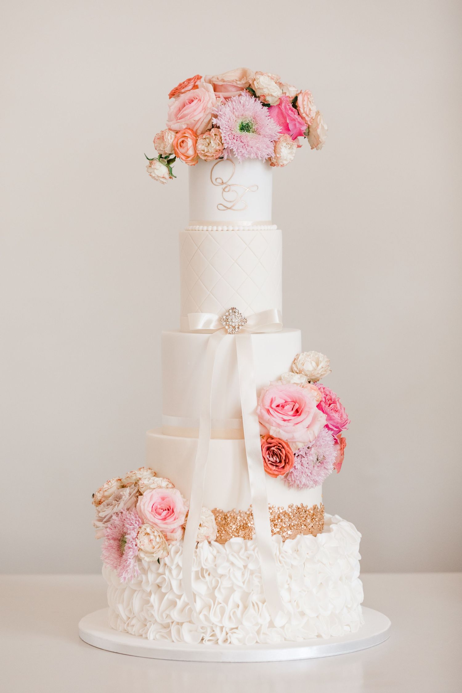 Elegant white wedding cake decorated with pink and peach roses.