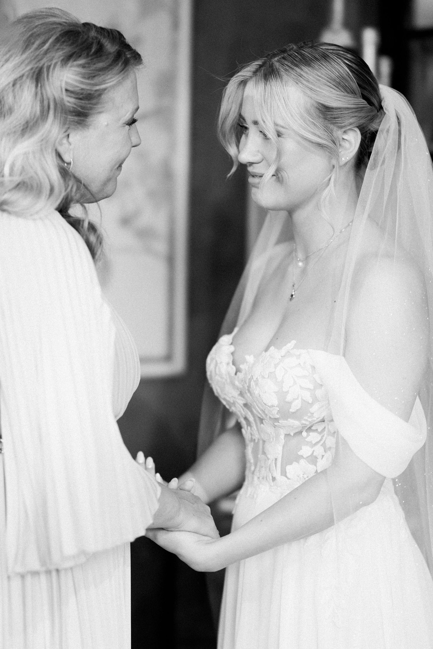 A tender black and white moment between two women sharing a joyful exchange on a wedding day.