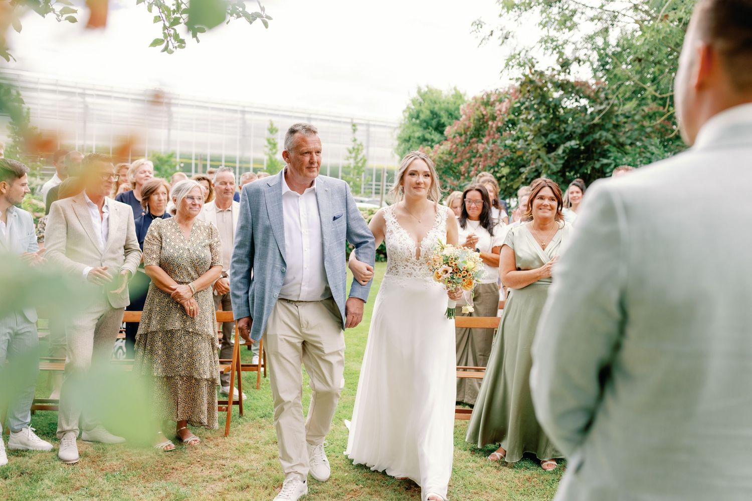 Wedding guests celebrate outdoors with colorful smoke bombs during a festive garden reception.