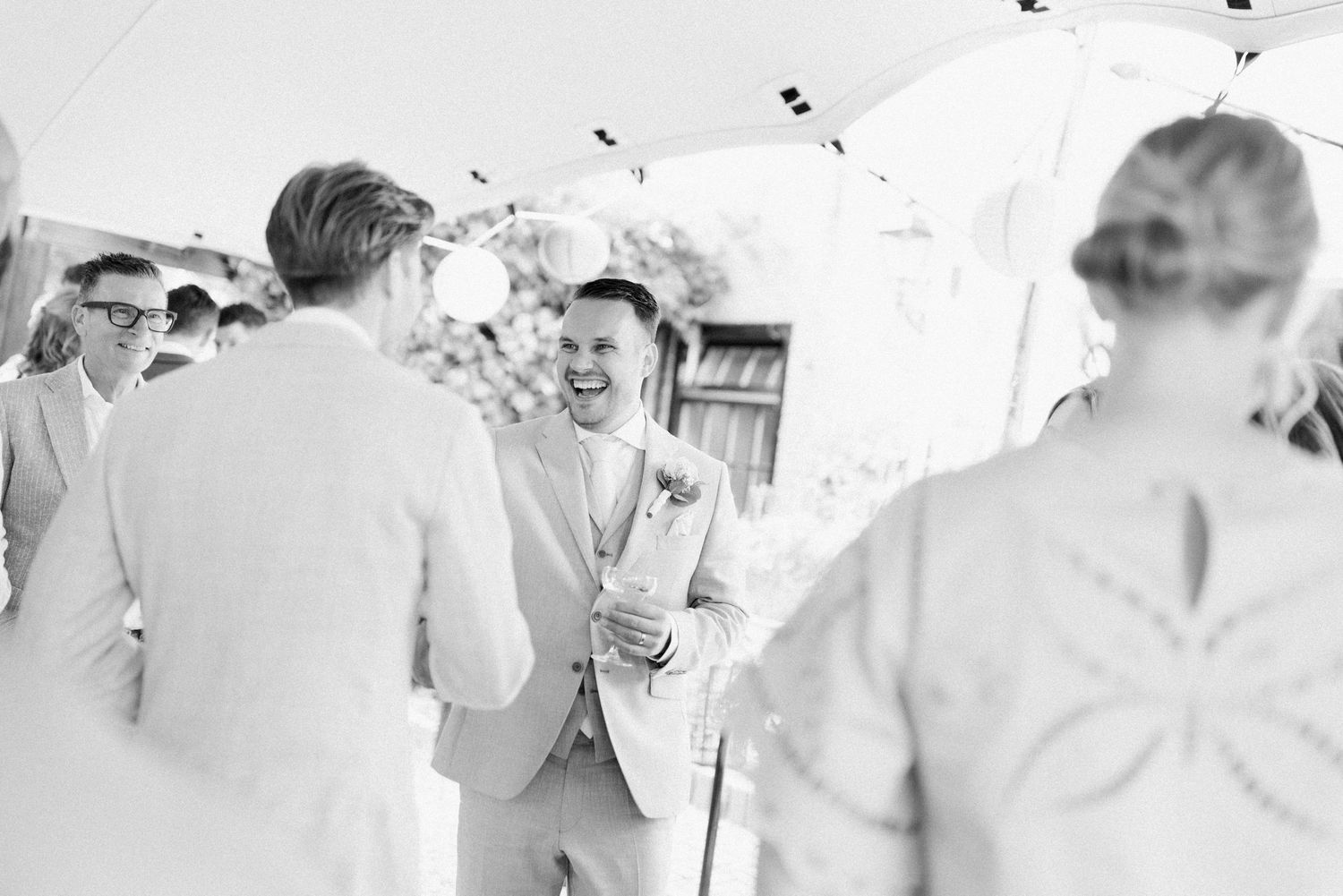 Wedding guests enjoy dancing and celebrating at an elegant outdoor reception under white tents and string lights.