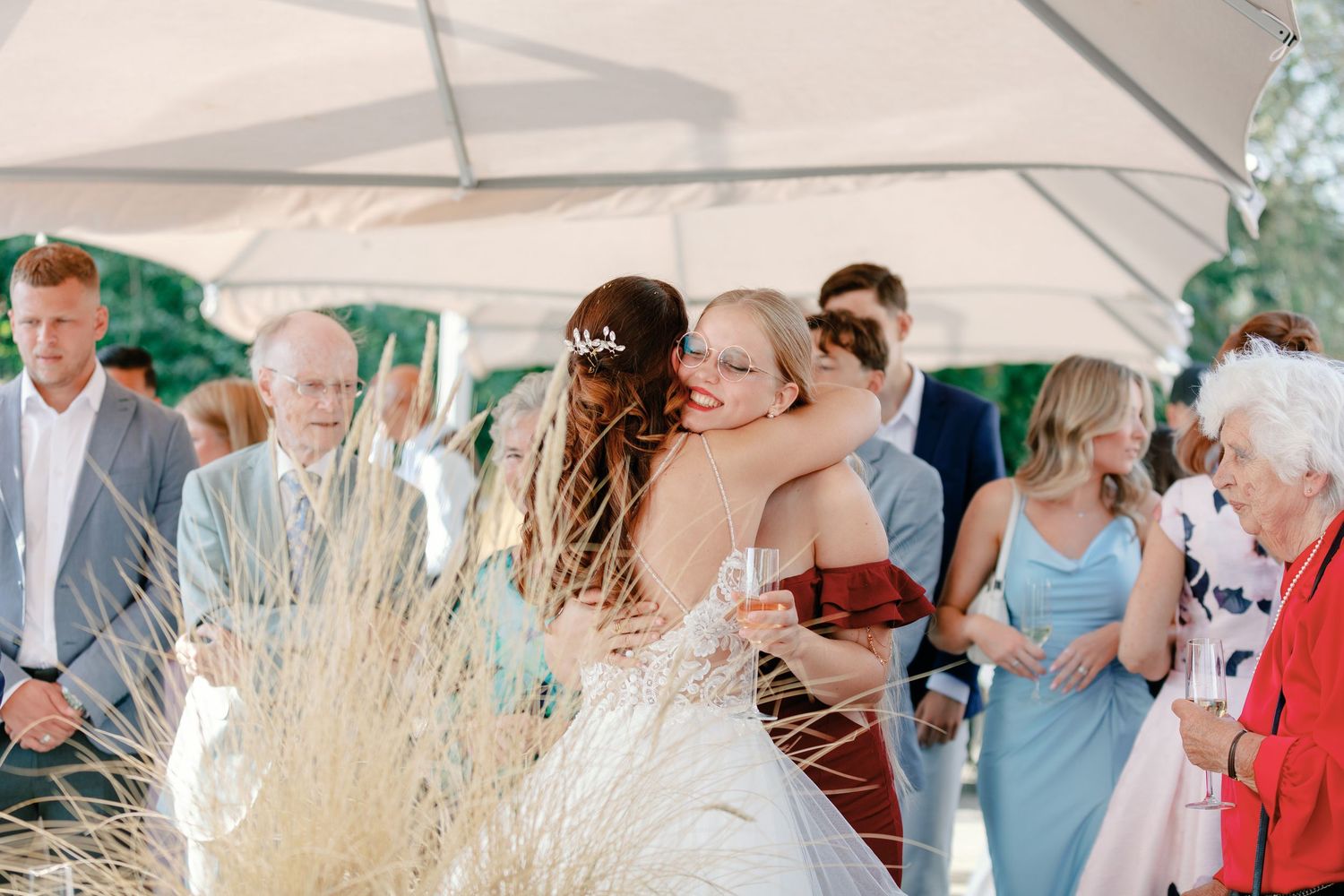 Wedding guests gathered under a white tent canopy for an outdoor celebration.