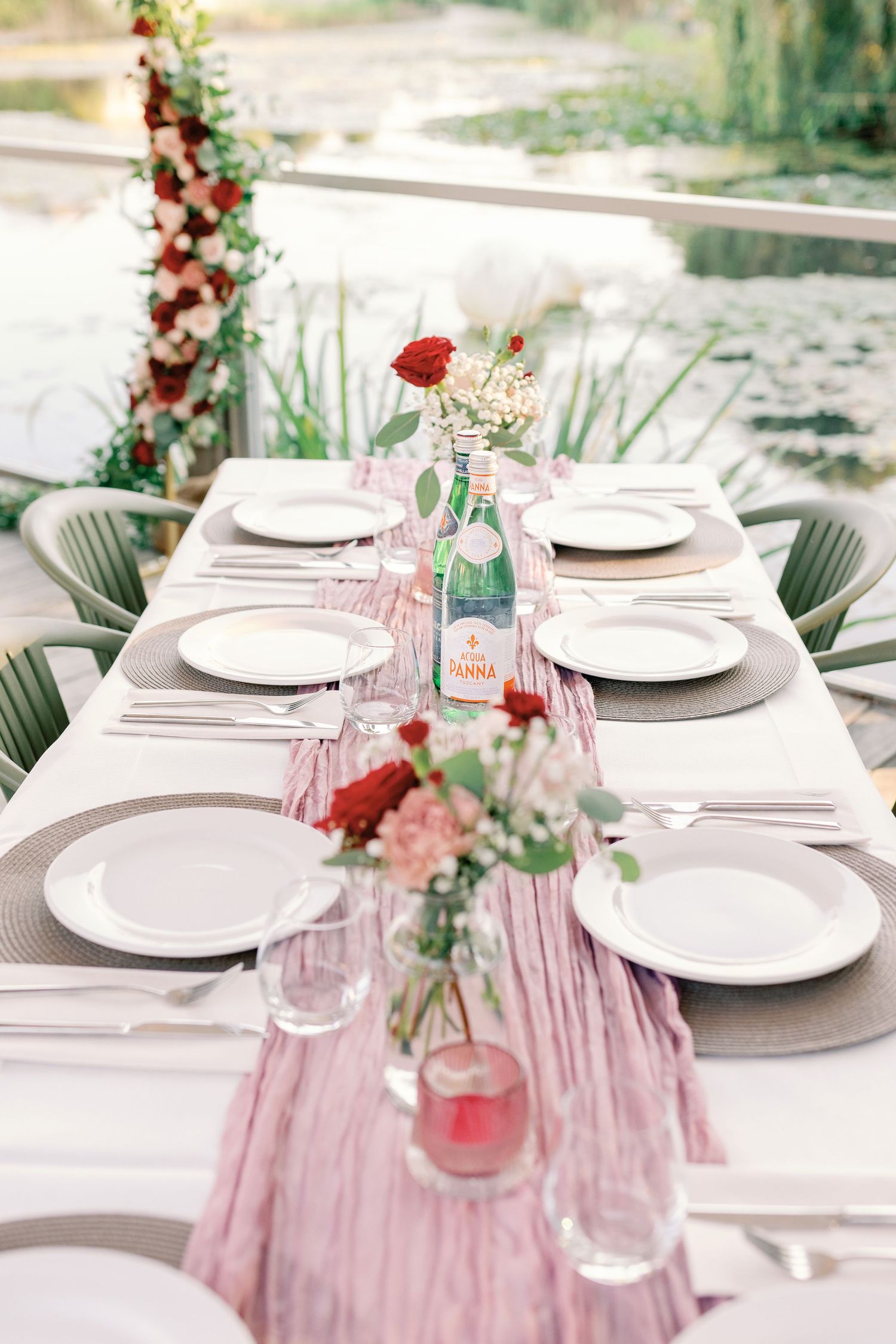 Elegant table setting with pink accents and white plates under outdoor umbrella.