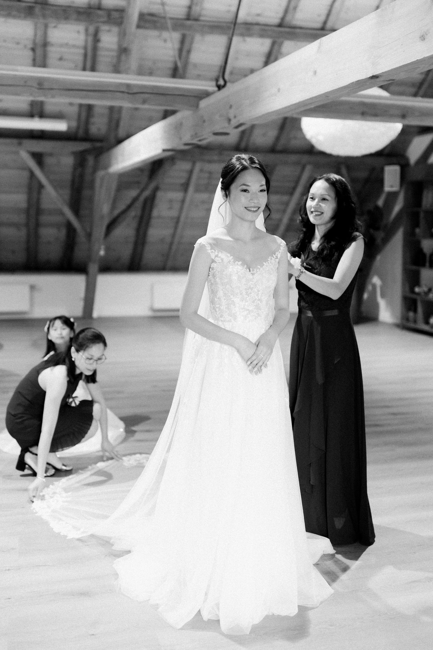 Wedding dress preparations in a spacious room with people working on final adjustments and styling.