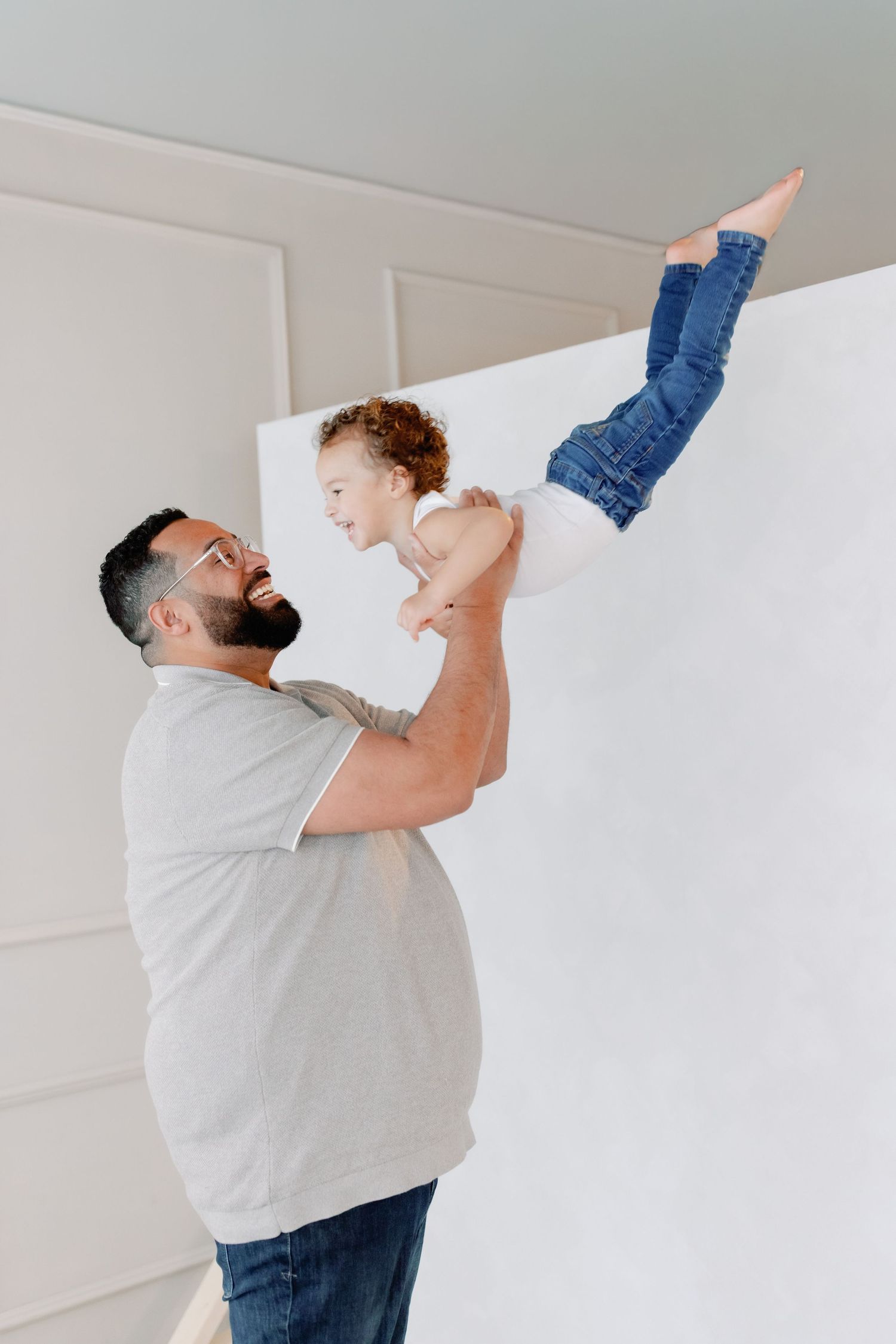 A person in a white t-shirt dances joyfully against a white wall in a sequence of dynamic movement poses.