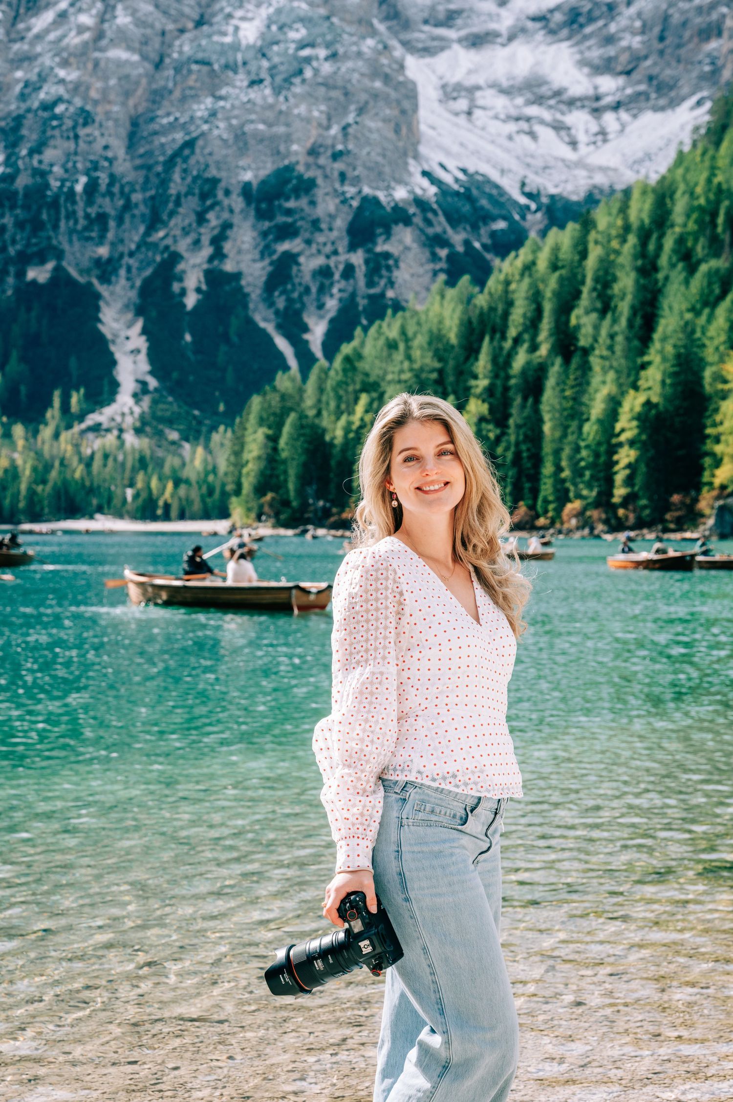 Scenic mountain lake landscape with evergreen trees and boats on turquoise water.