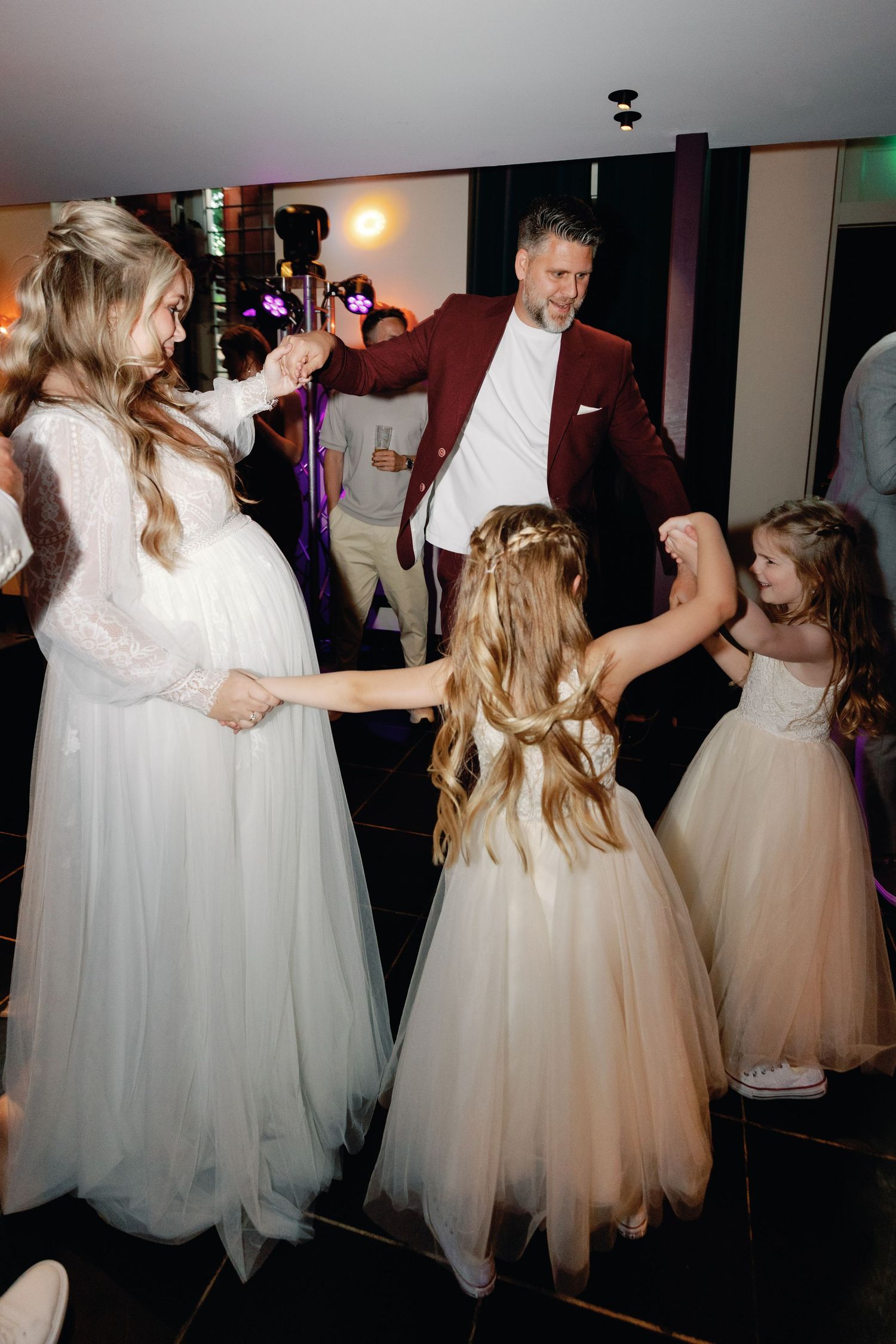 Group of dancers in flowing white tulle dresses twirling together on a dimly lit dance floor.