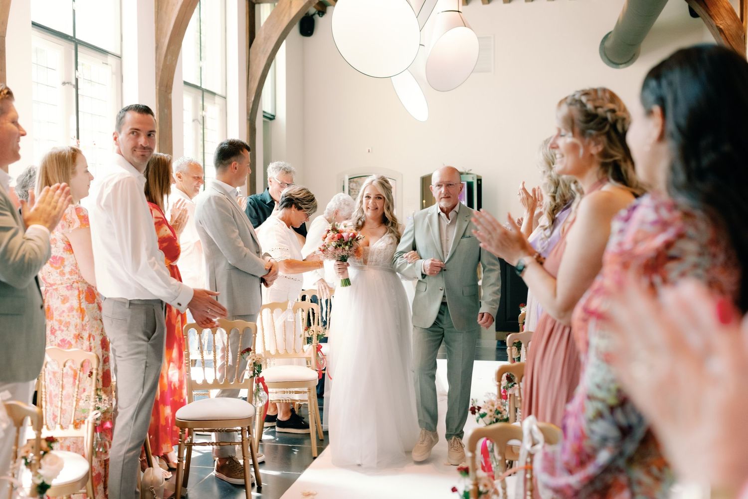 Wedding guests dance and celebrate together on a dance floor at an indoor reception venue.