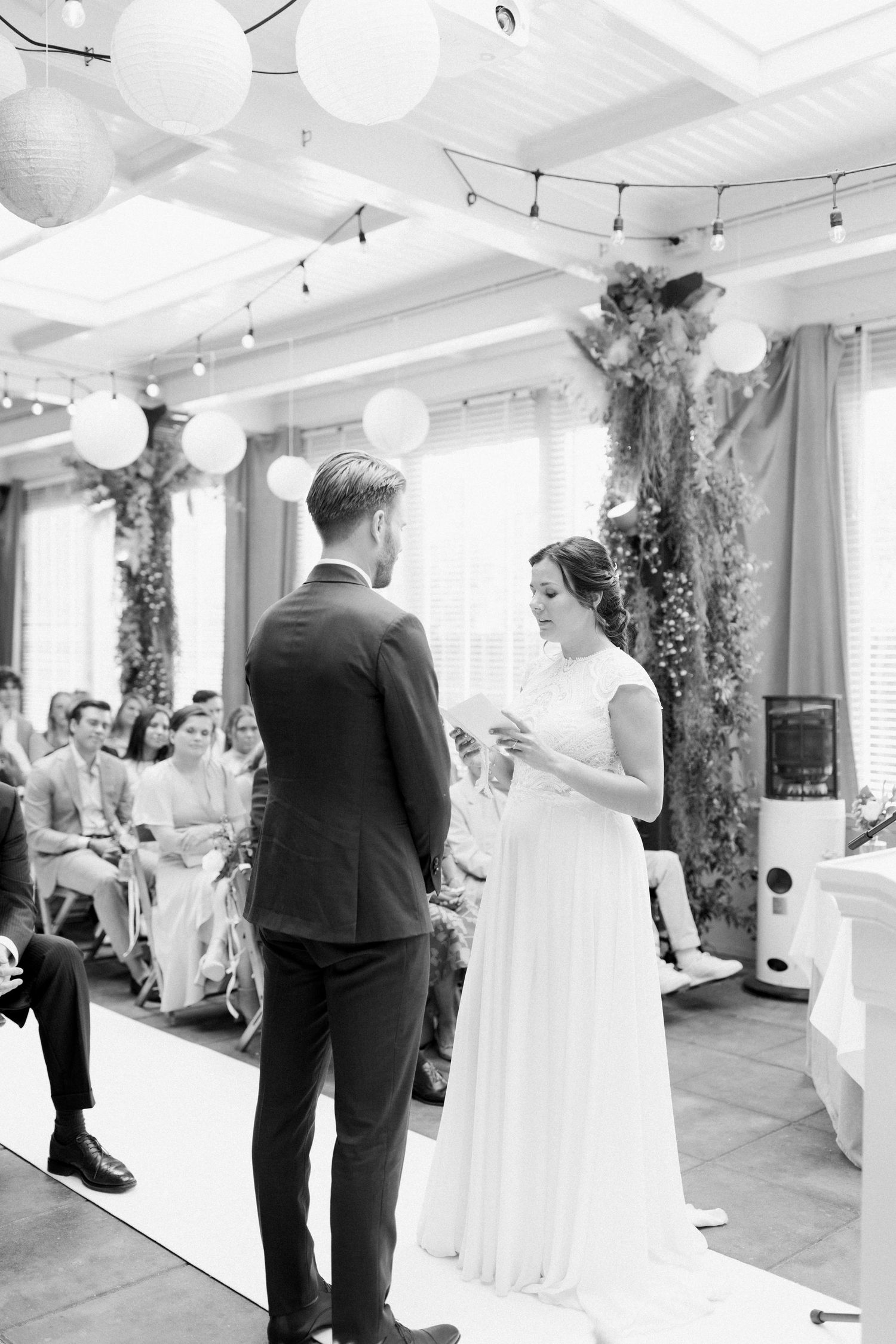Black and white wedding reception photos showing guests dancing and celebrating at an indoor venue with string lights.