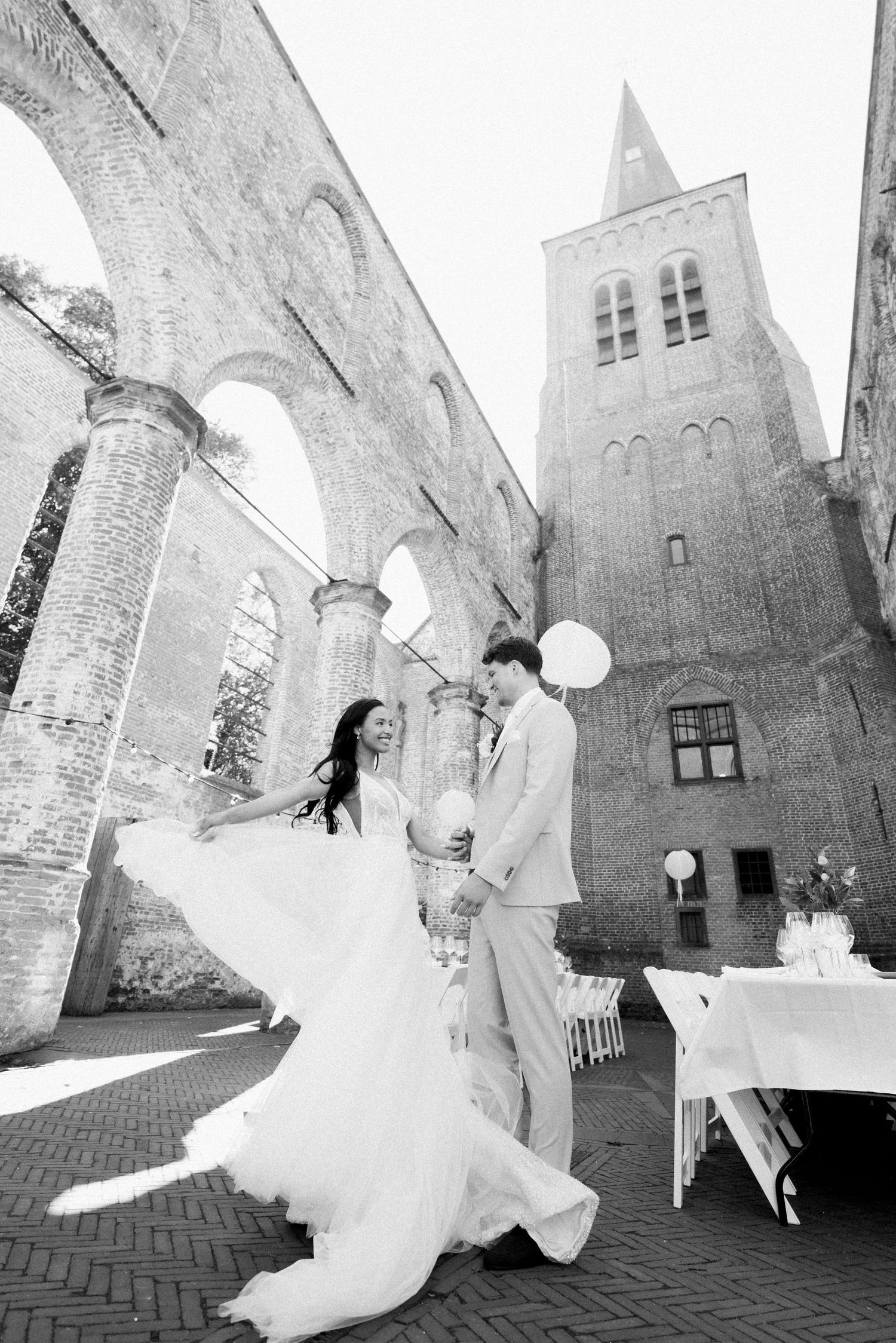 Black and white wedding photos showing a couple dancing and twirling in front of a historic church building.