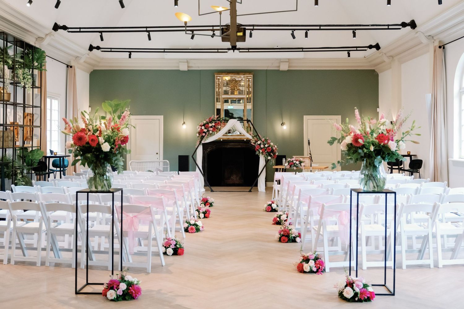 A modern wedding ceremony space with white chairs and black lantern decor arranged in rows for an elegant indoor event.