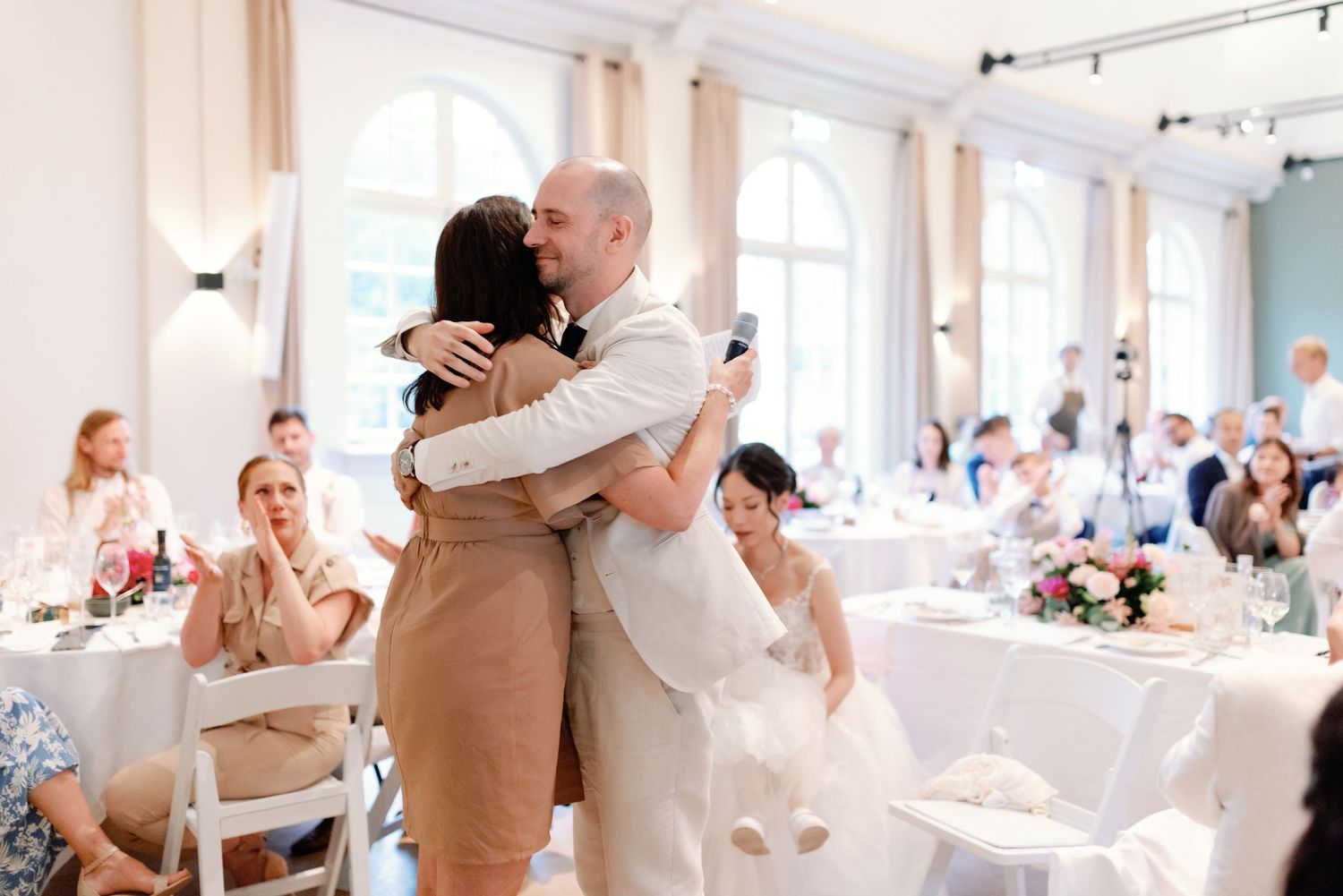 Couples dancing together during a wedding reception in a bright white ballroom.