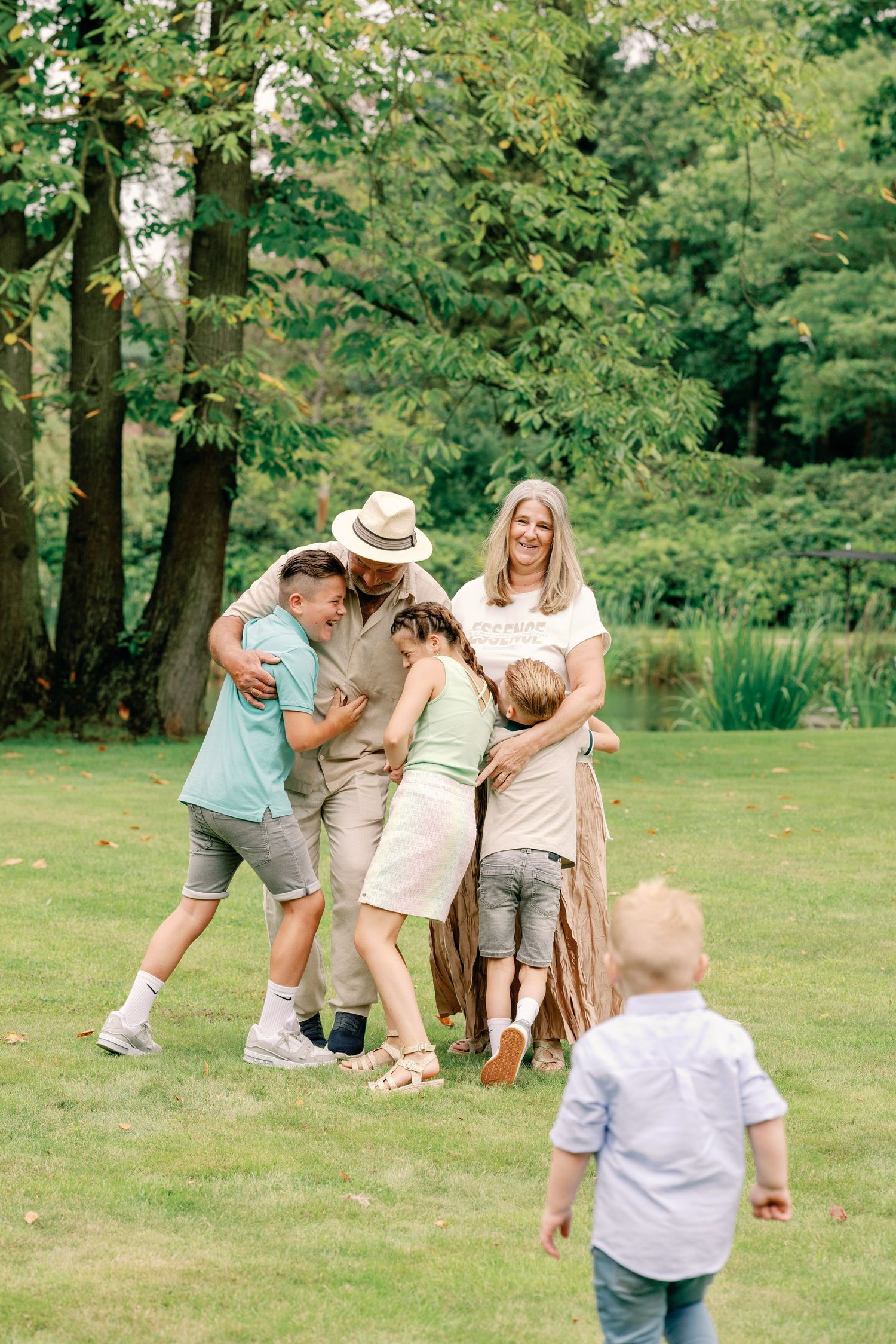 Candid family photo session showing playful interactions in a sunny park setting.
