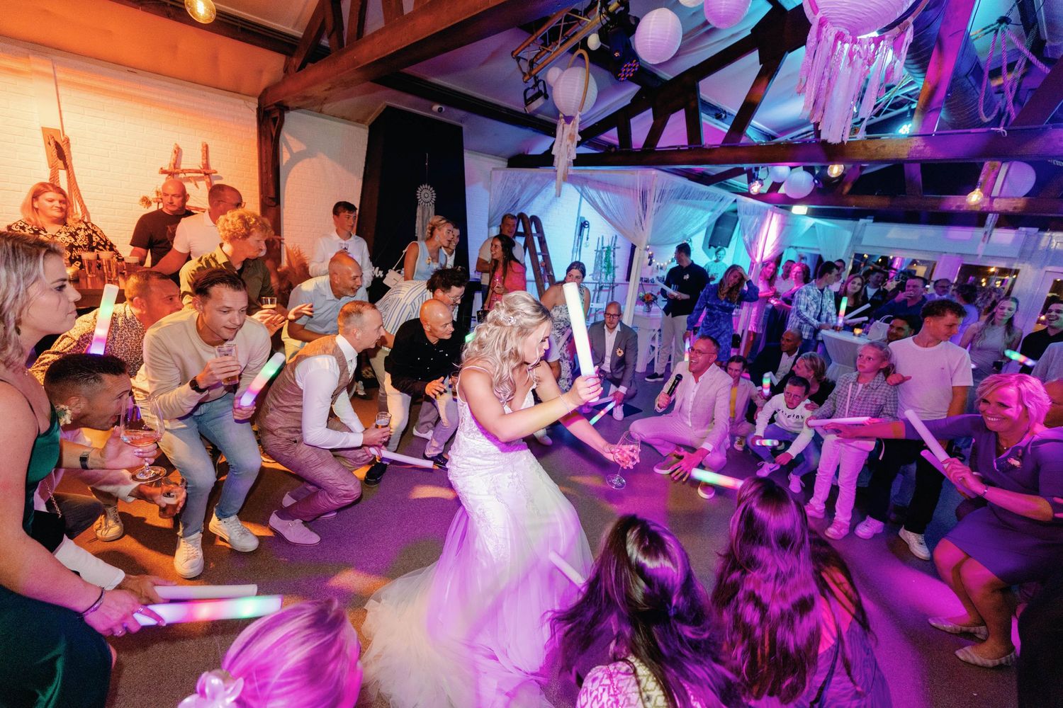 A vibrant dance party scene with colorful purple and blue lighting illuminating a crowded dance floor.