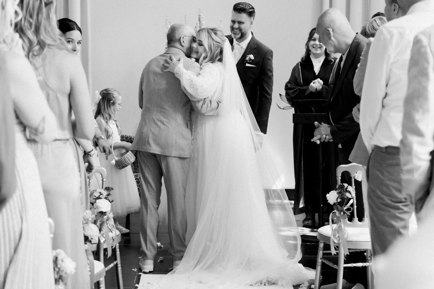 A wedding party celebrates during a reception with dancing and joyful moments in black and white photography.