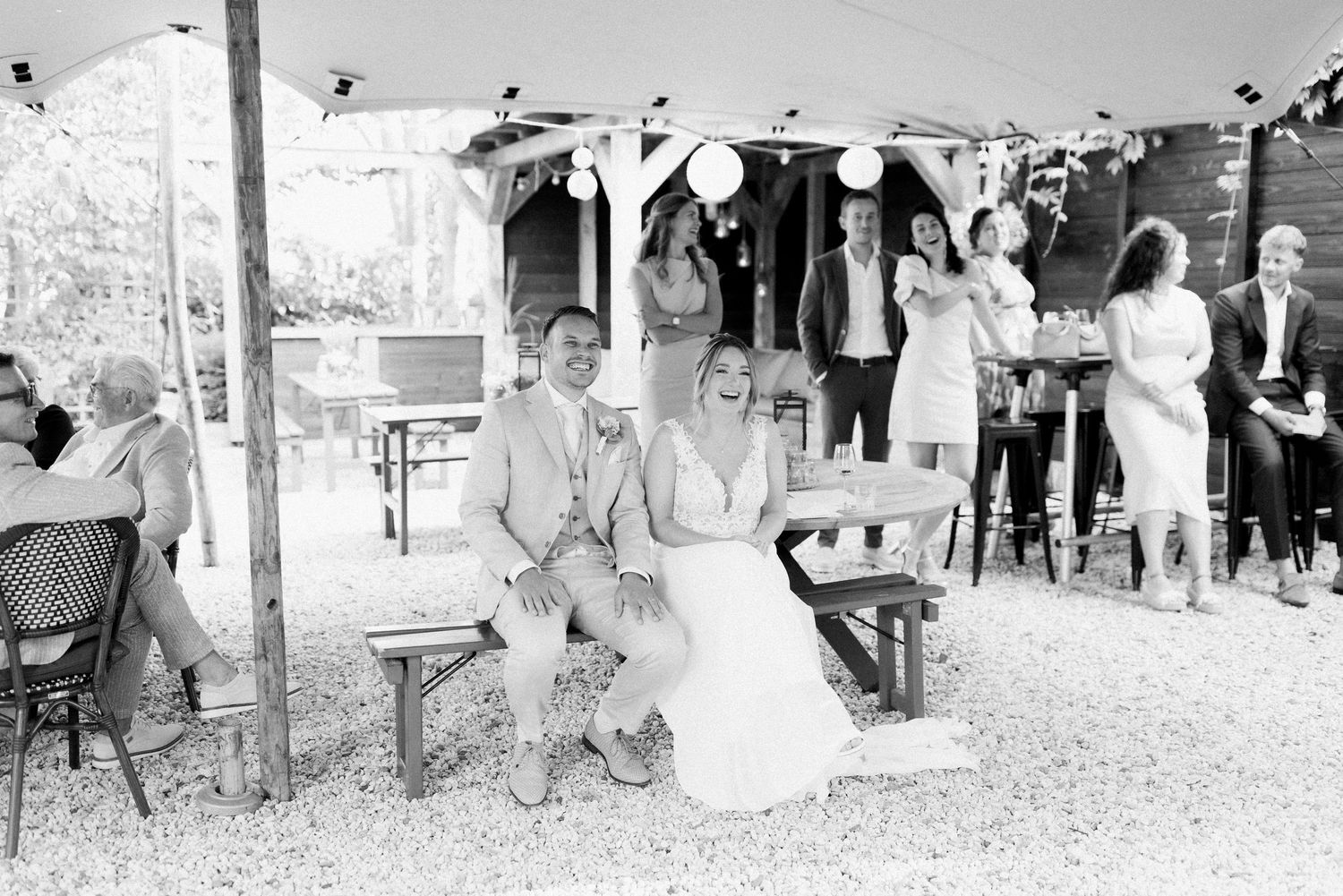 A black and white panoramic photo shows a group gathering at an outdoor event with tables and chairs.