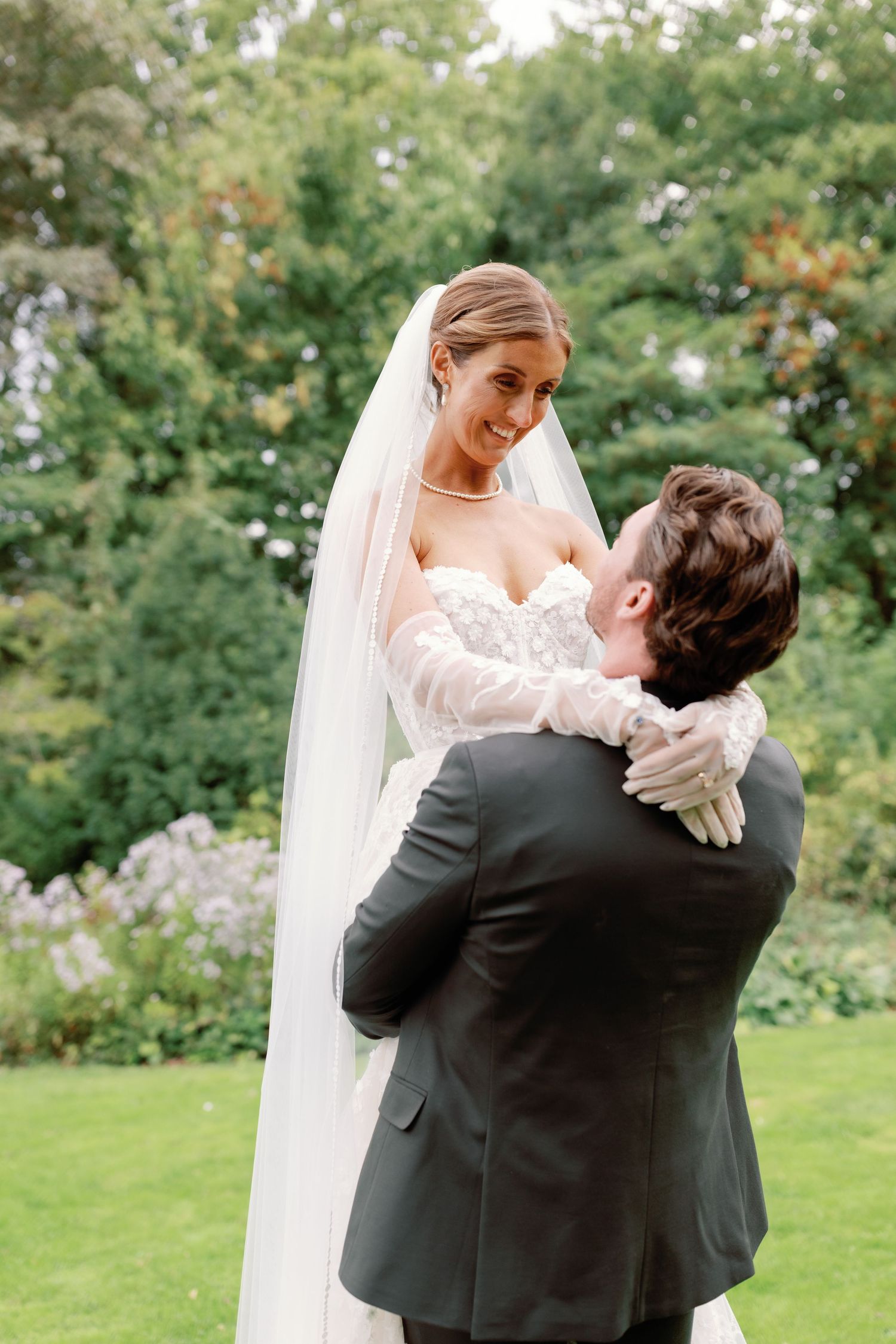 A bride and groom share an intimate embrace while dancing in a lush garden setting.