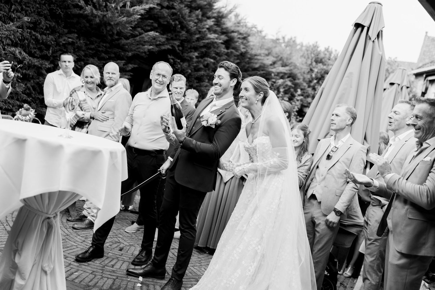 Wedding guests gather outdoors under a white tent for a joyous celebration.